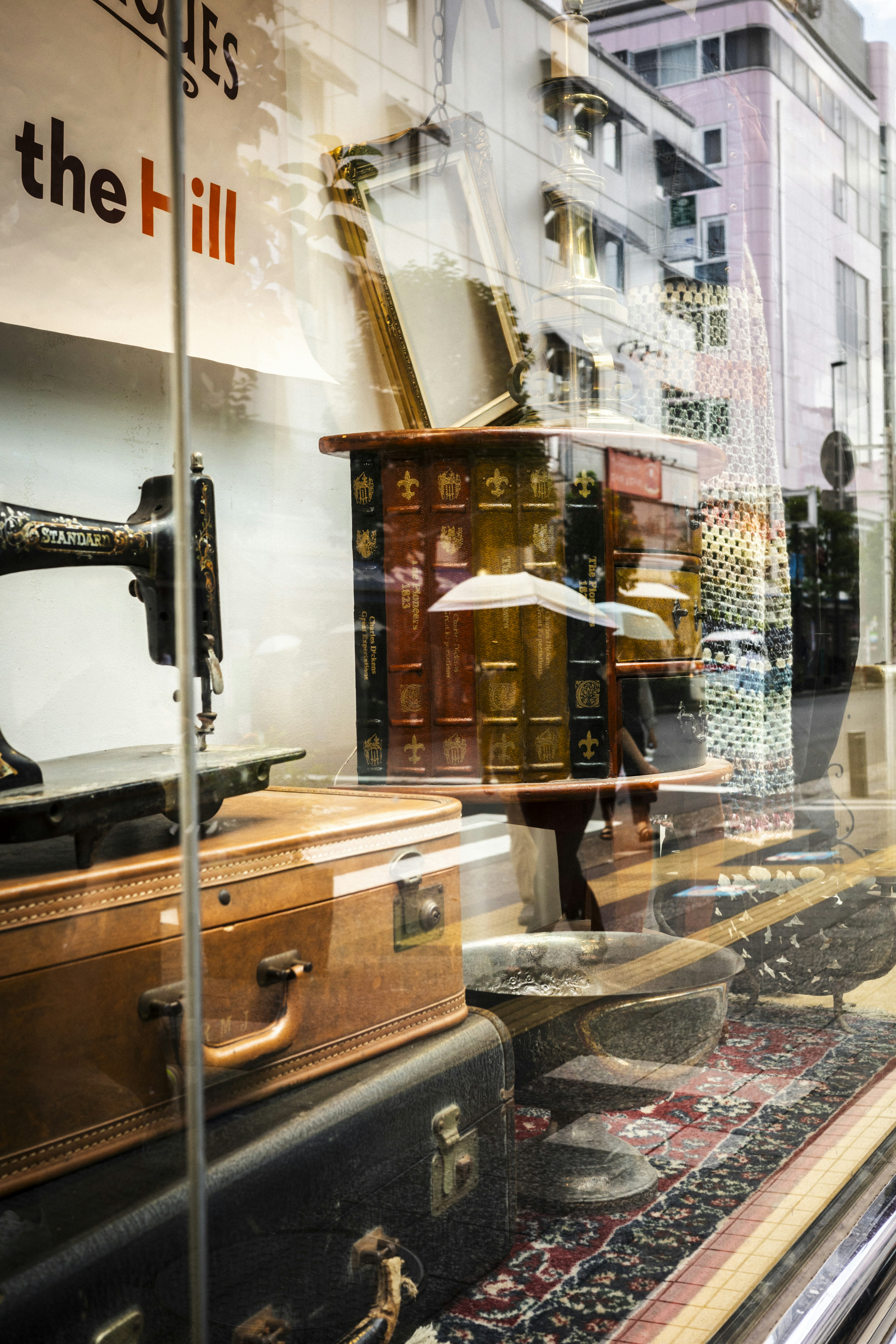 Une machine à coudre vintage et de vieilles valises exposées dans une vitrine