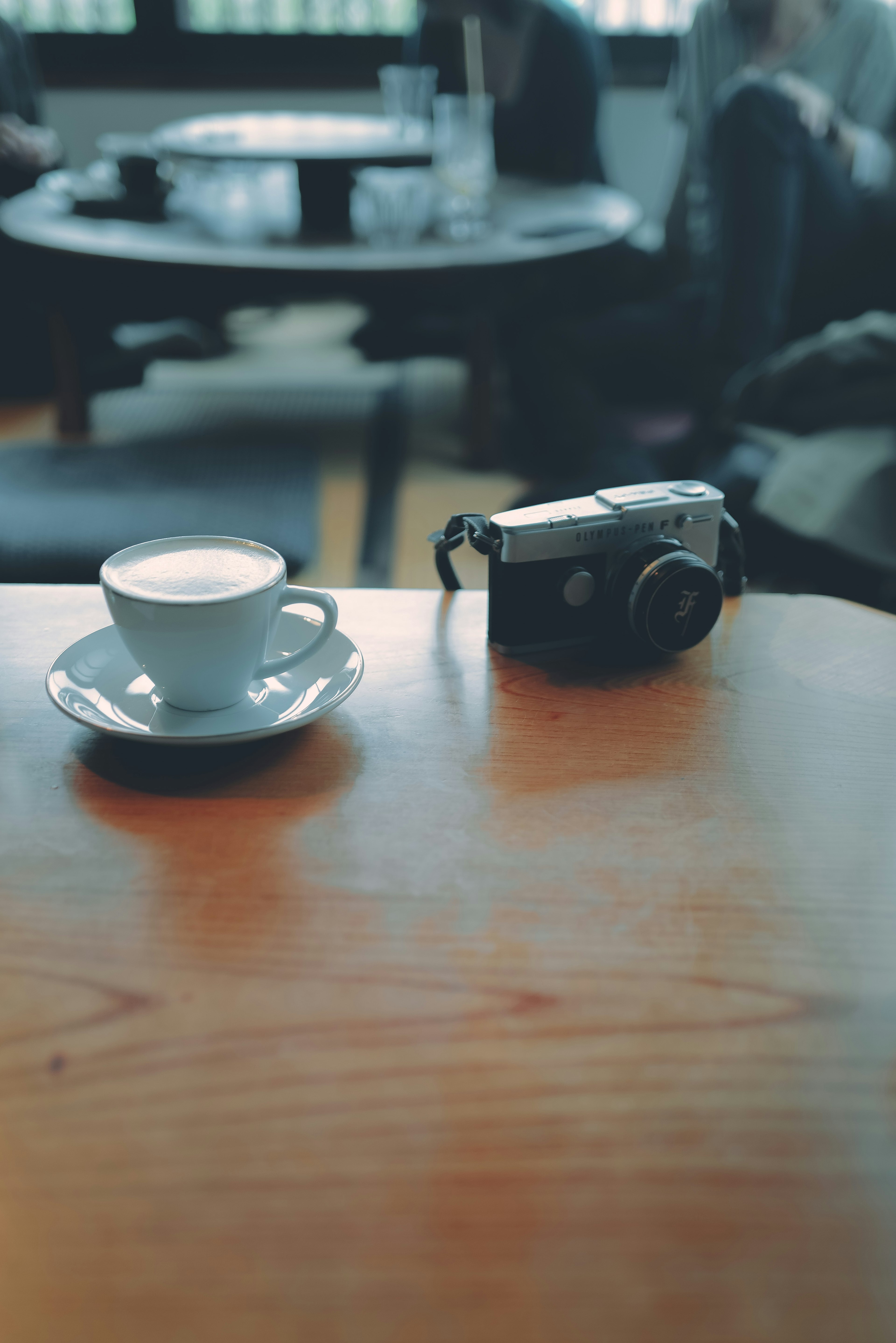 Foto de una pequeña taza de café y una cámara antigua sobre una mesa de madera