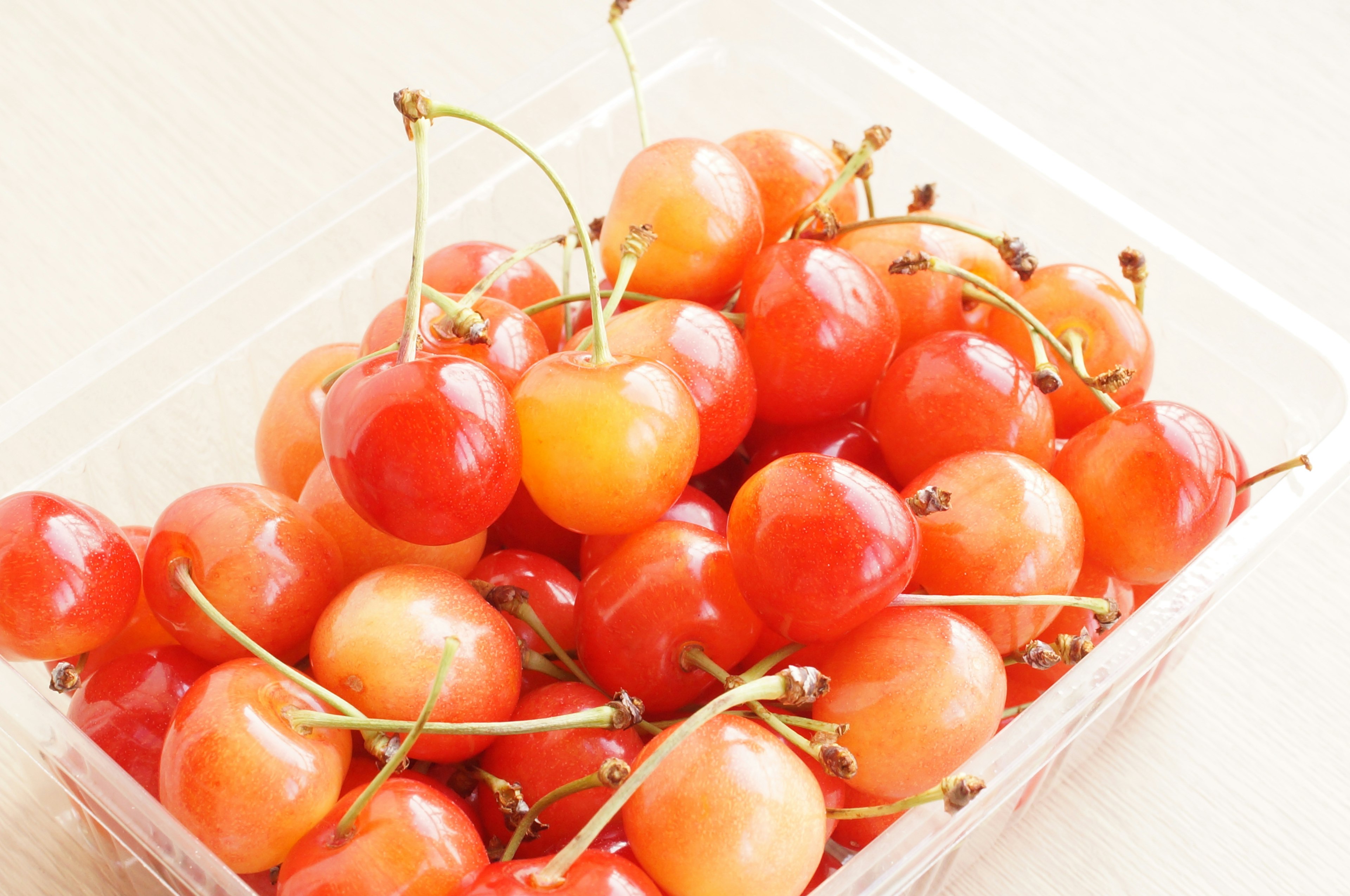 A transparent container filled with red and orange cherries