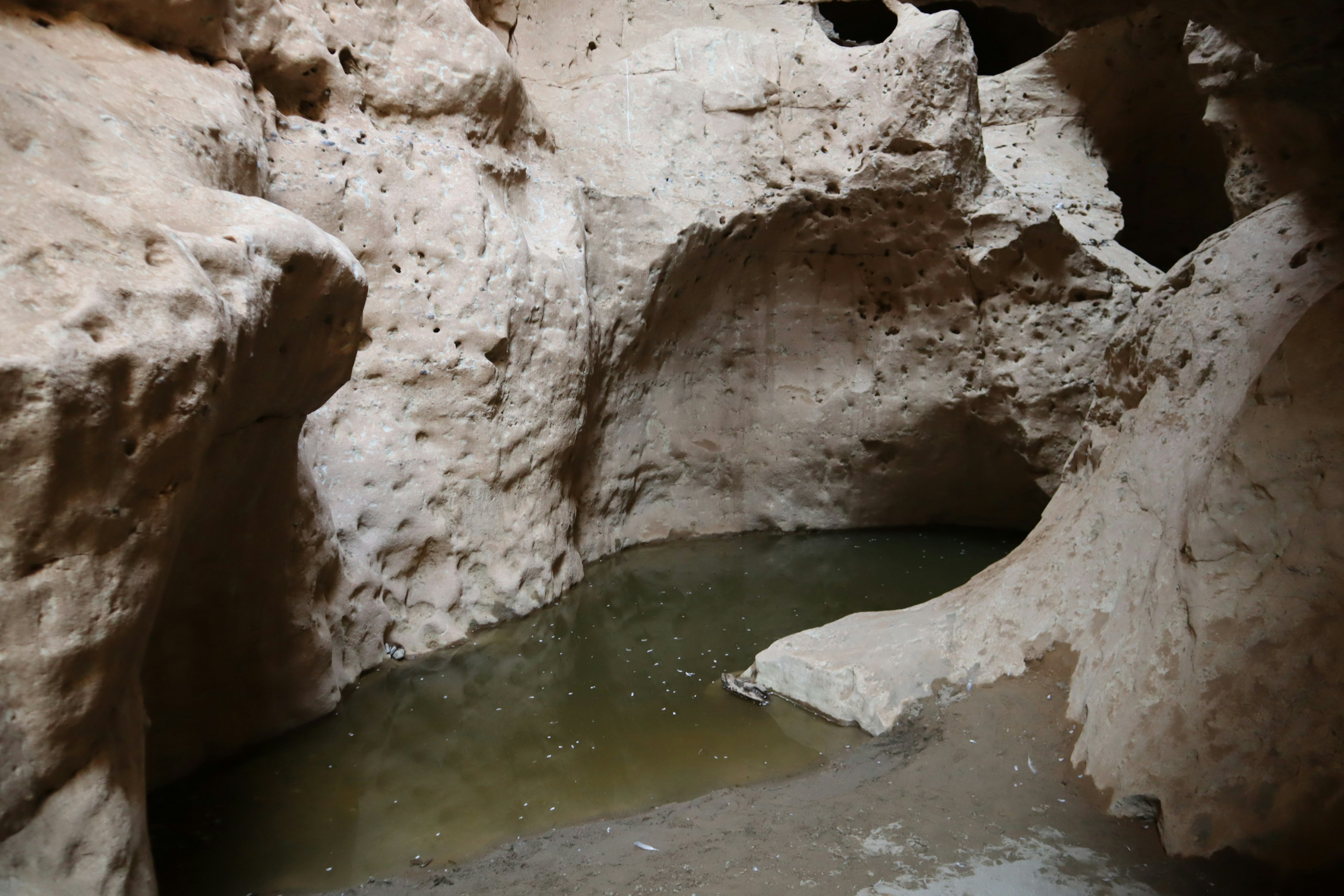 Interior of a cave with a shallow water pool and rocky walls