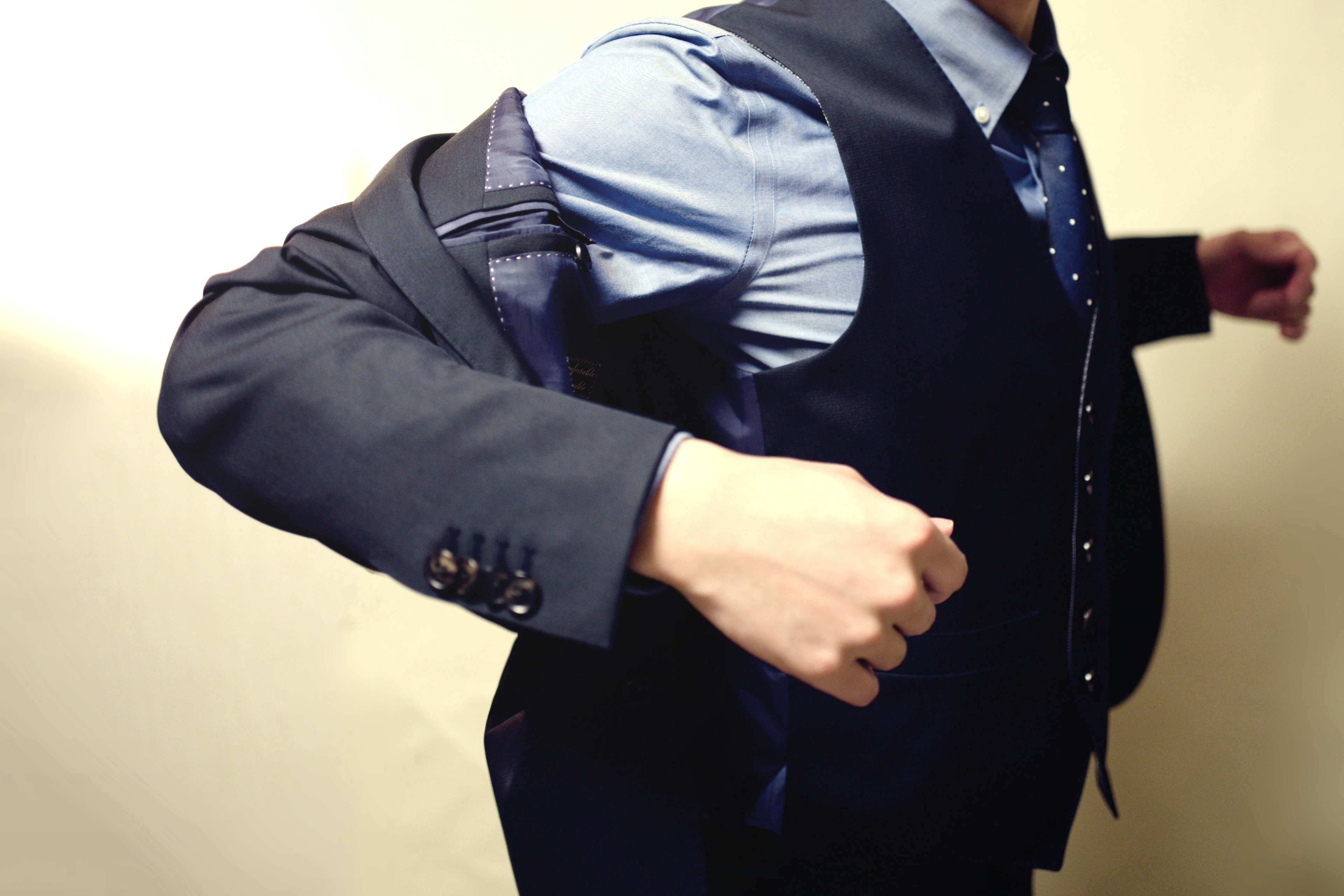 A man putting on a suit jacket with a formal shirt