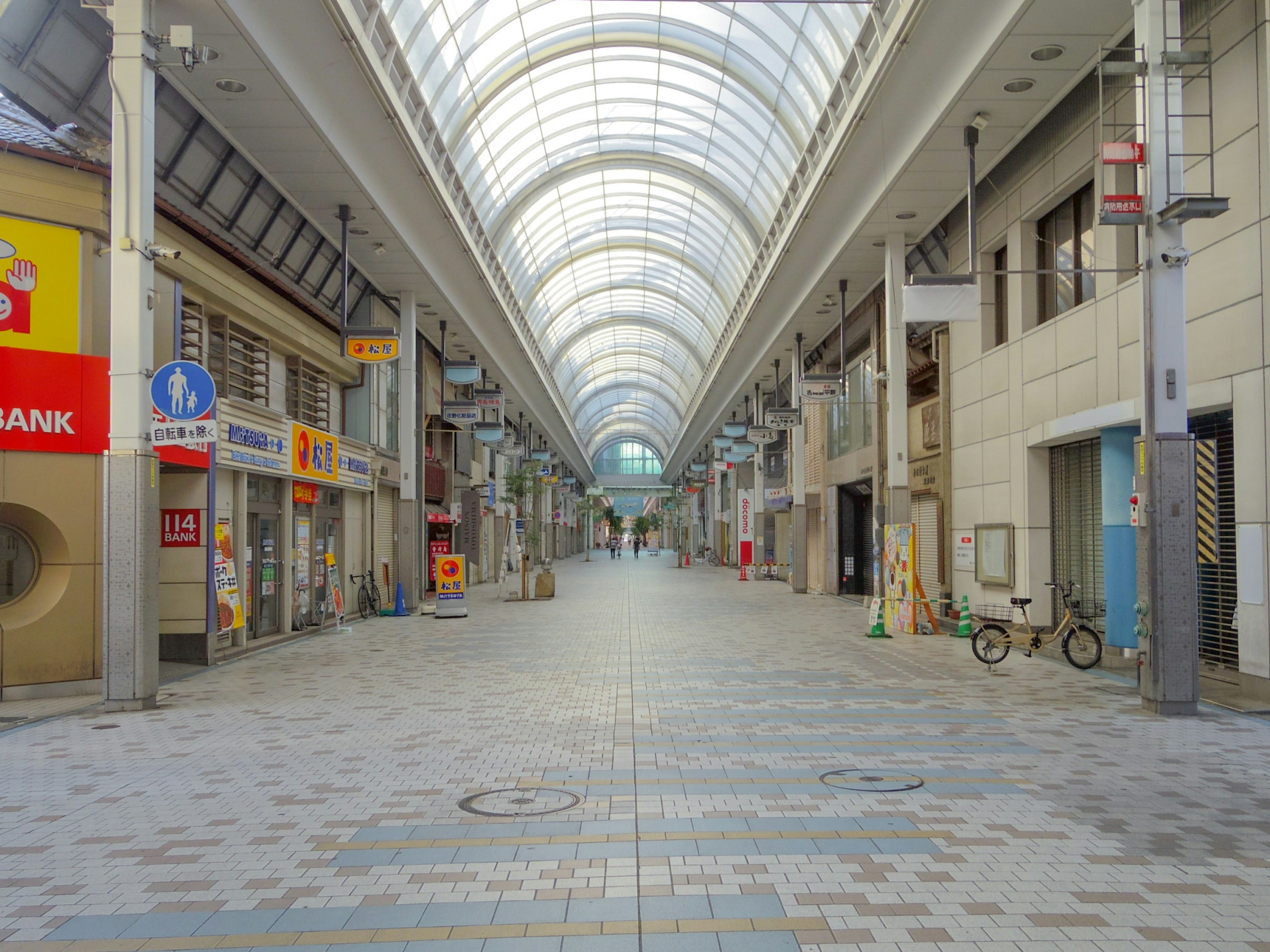 Wide interior of an arcade shopping street with empty pathway and glass roof