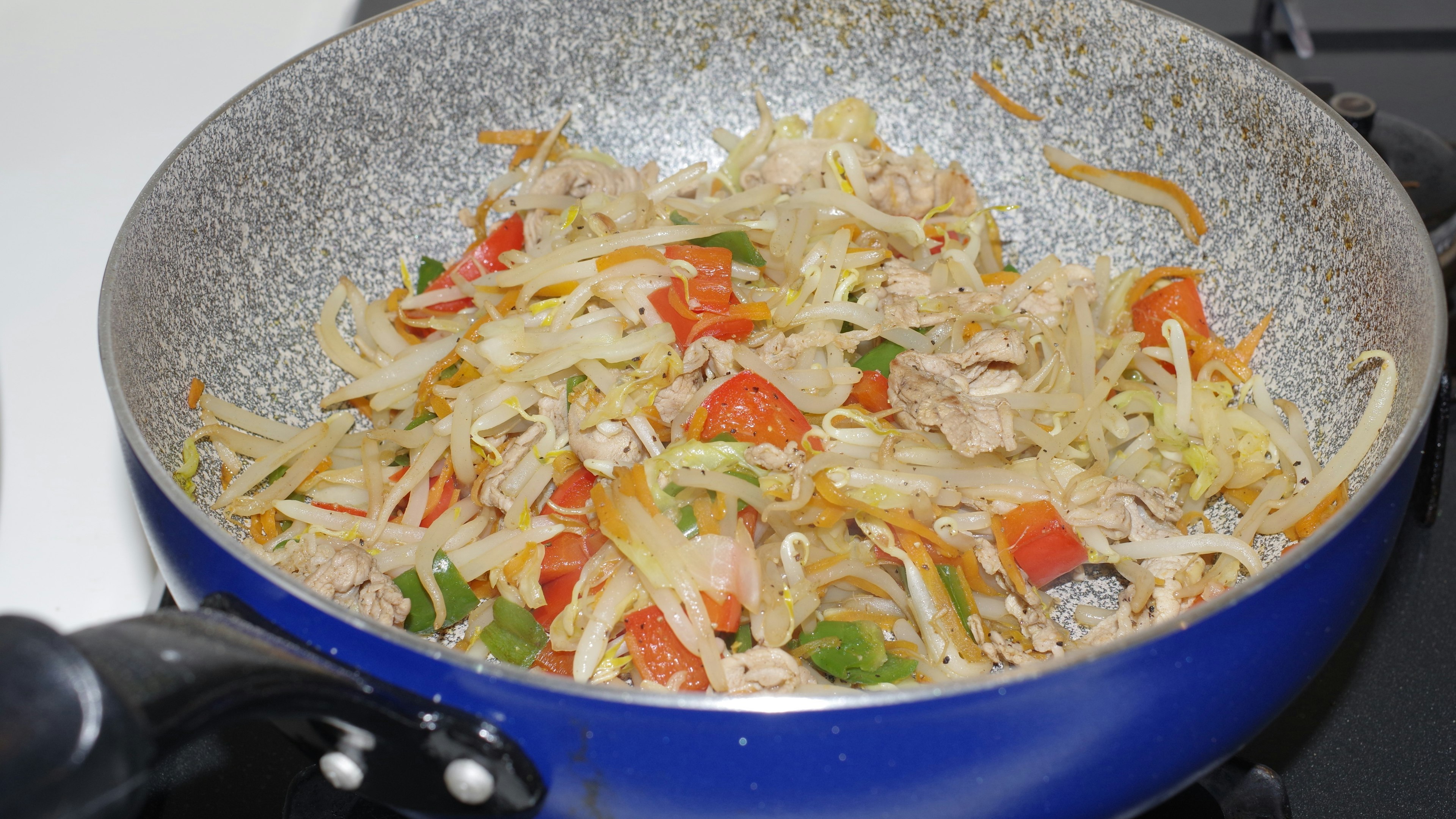 青い鍋で調理された野菜と鶏肉の炒め物