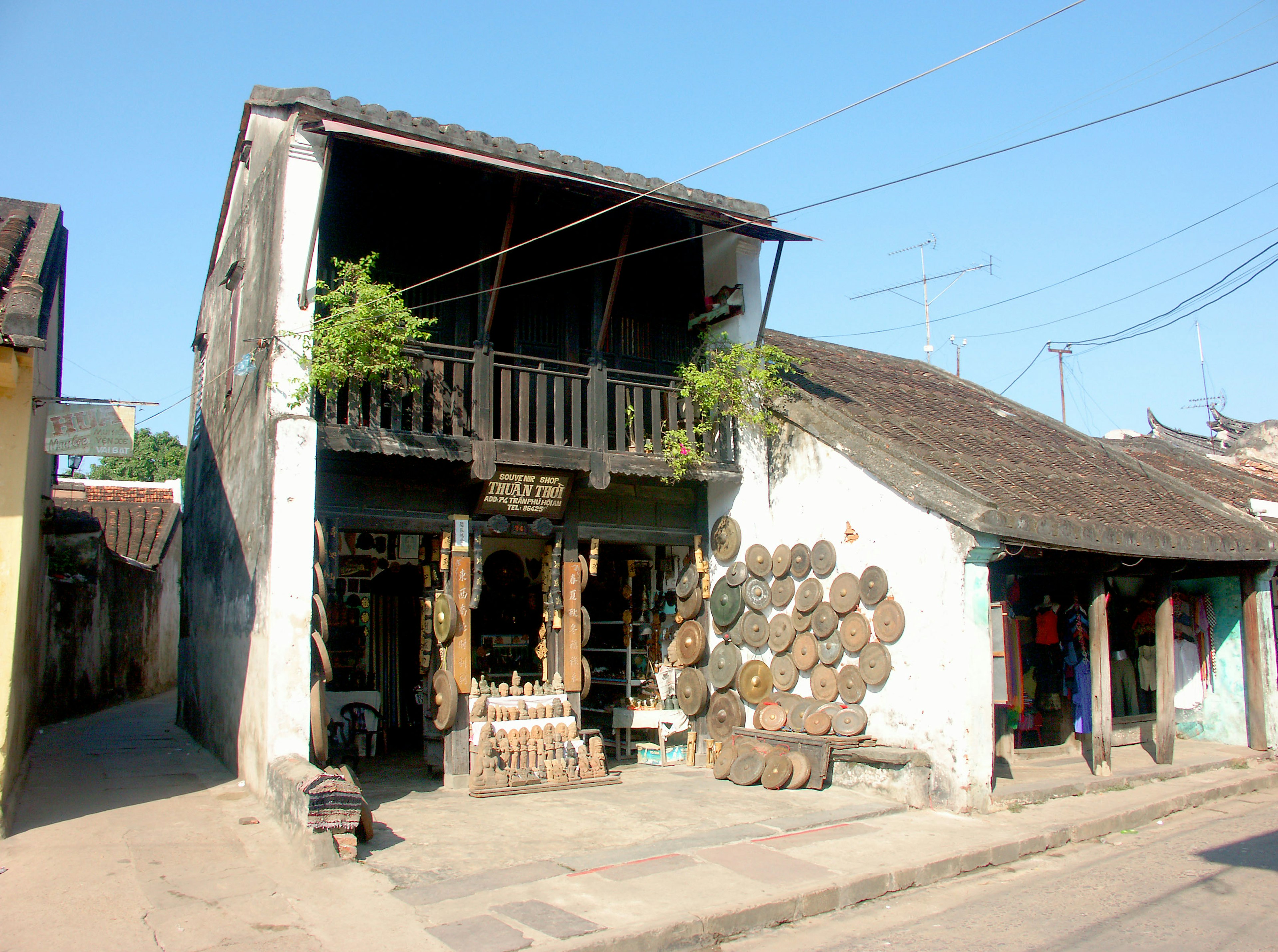 Eksterior rumah kayu tua dengan tanaman hijau dan elemen rustic