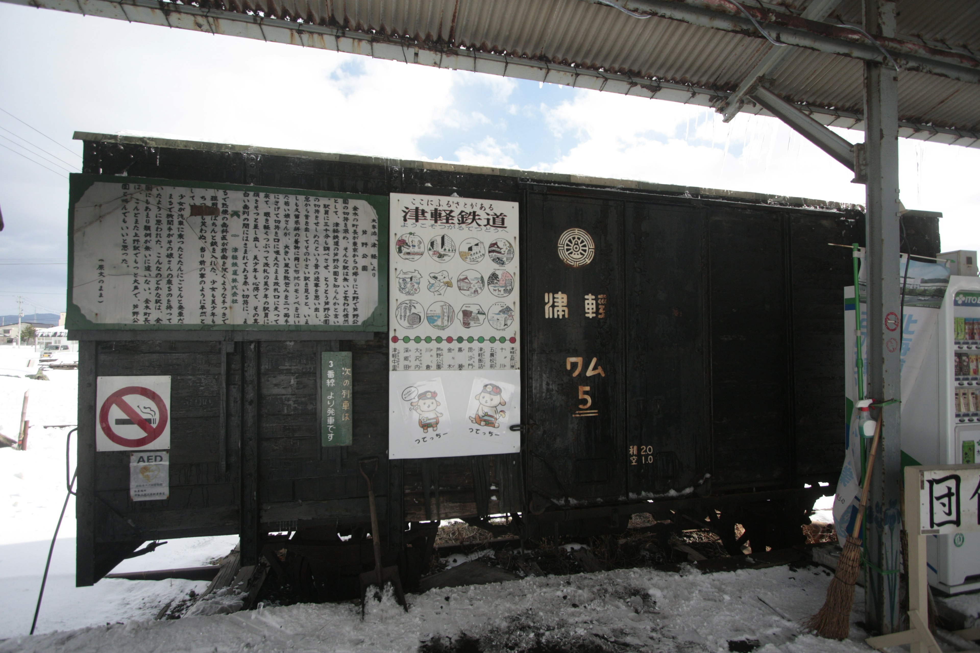 雪に覆われた駅での古い緑色の貨車に掲示された案内板