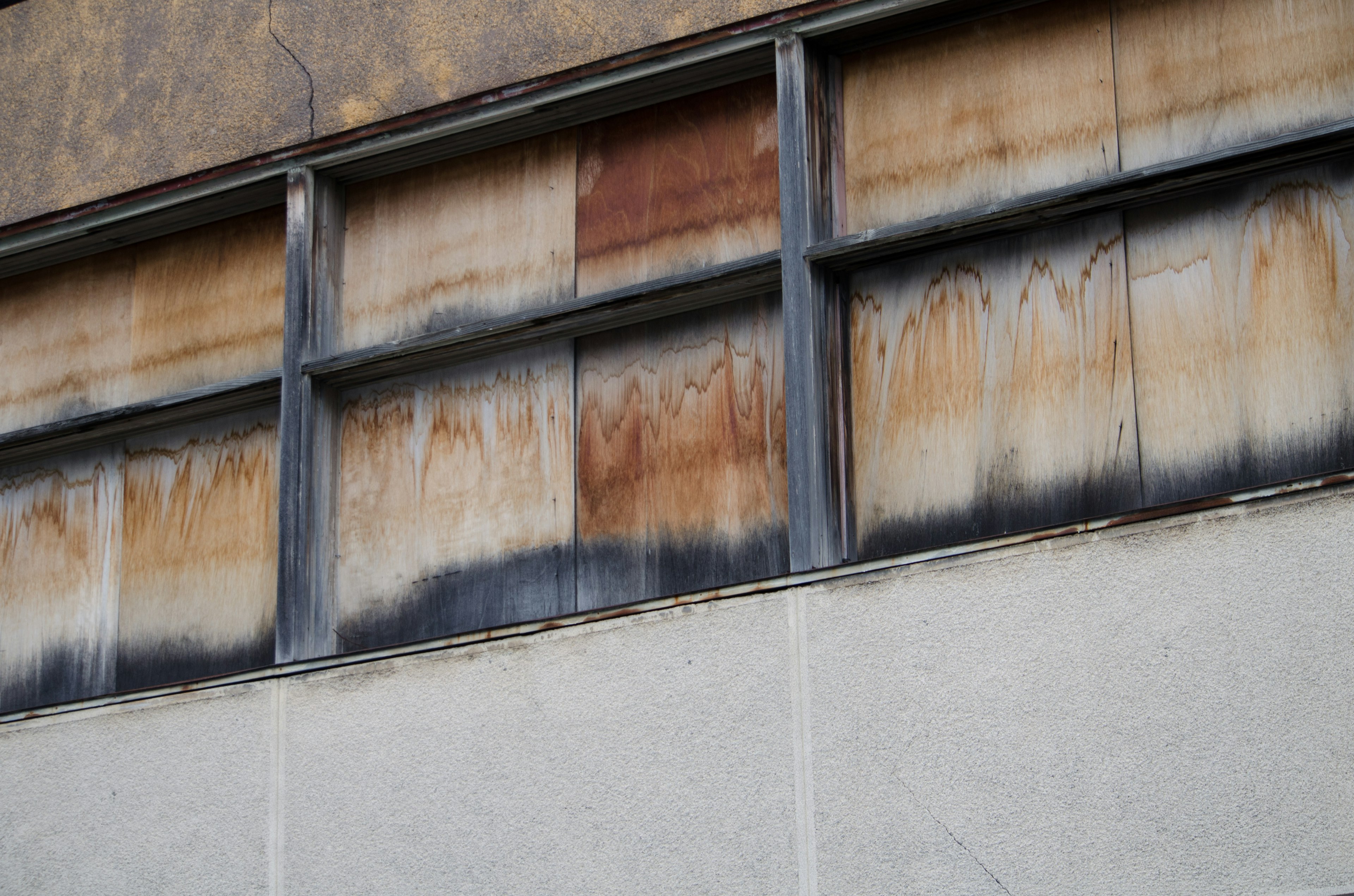 Rostige Fensterrahmen und verblasste Farbe an der Wand eines alten Gebäudes