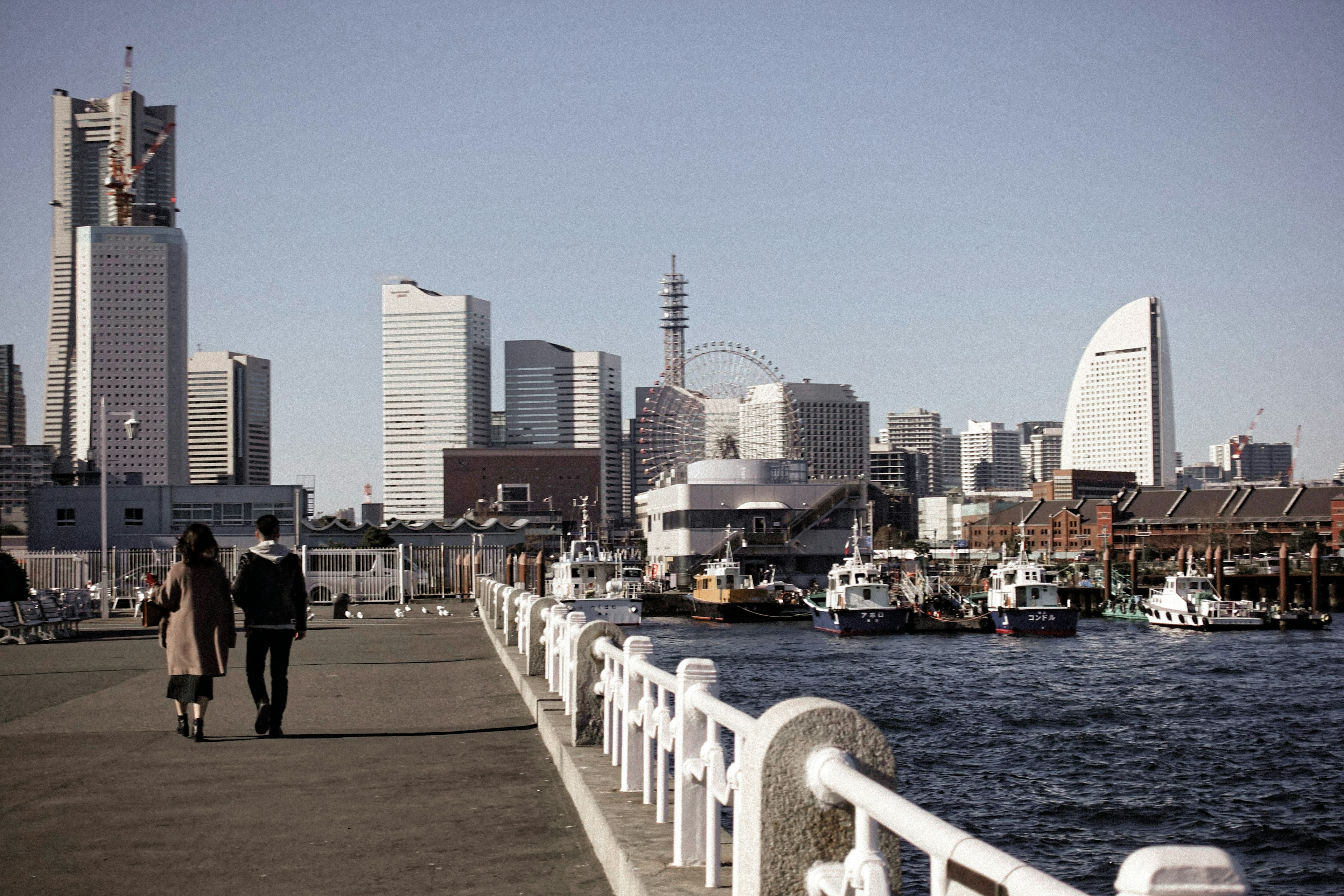 Pareja caminando por el puerto de Yokohama con rascacielos al fondo