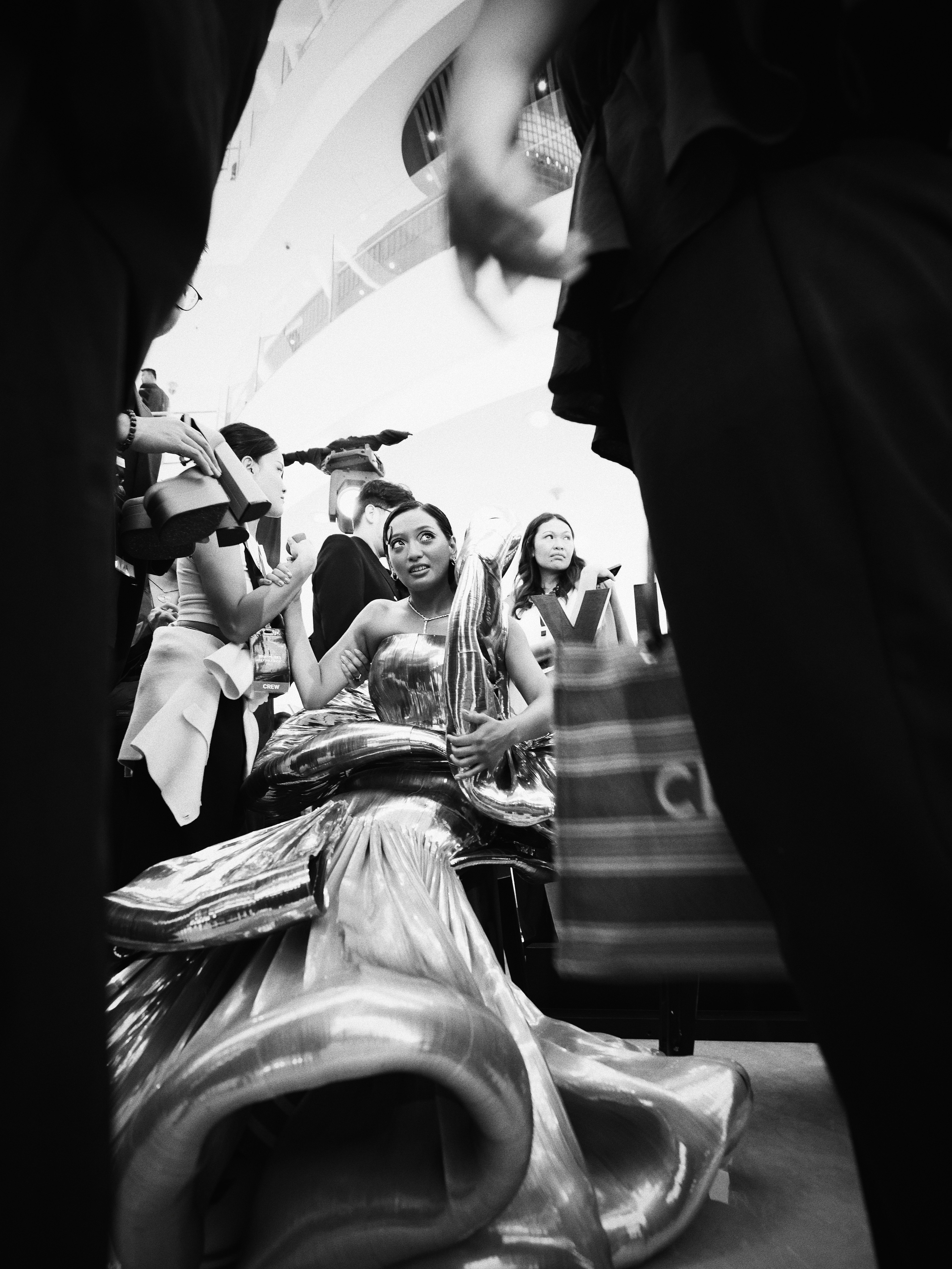 Black and white photo of a woman in a glamorous dress sitting among a crowd