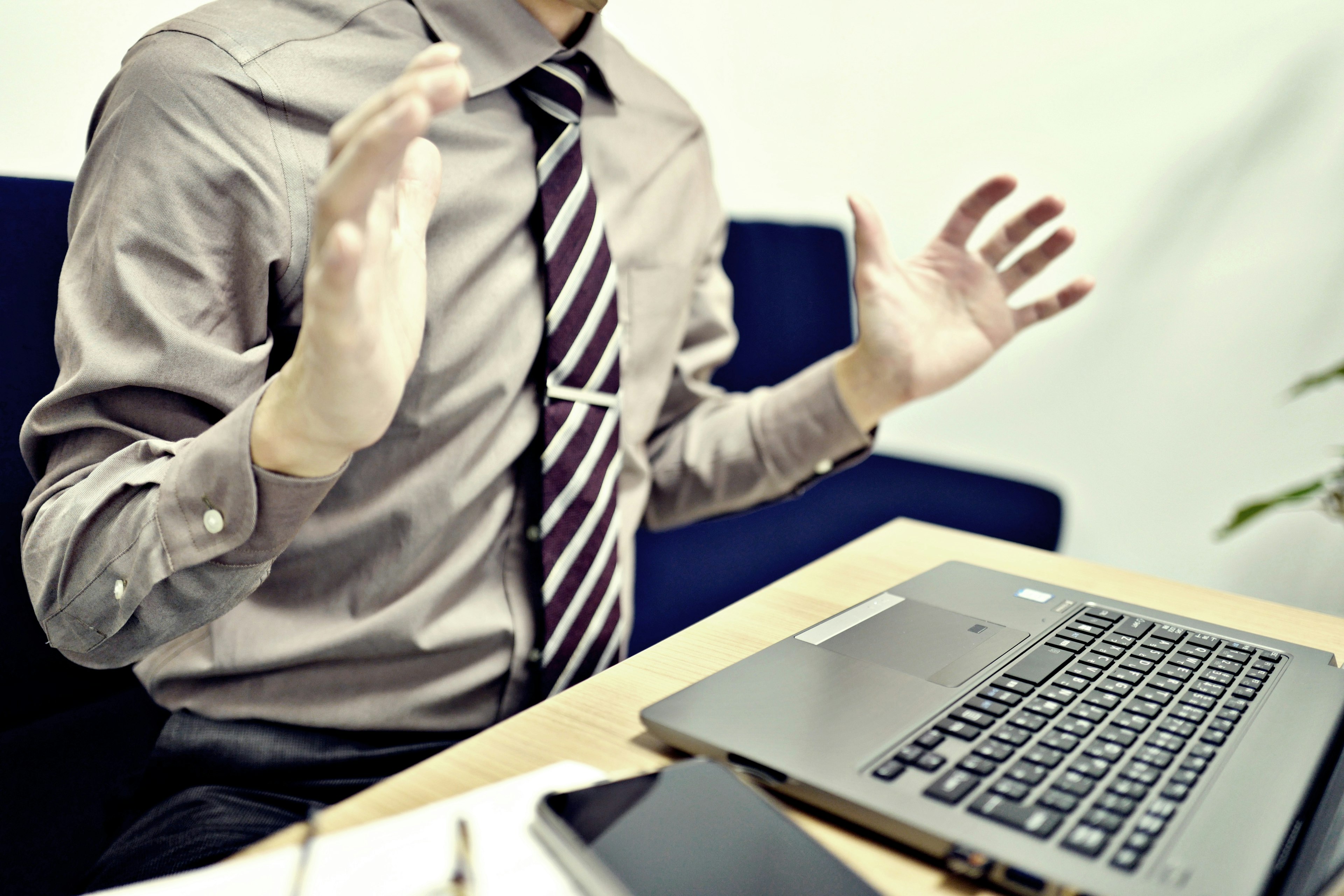 A man gesturing with hands in front of a laptop