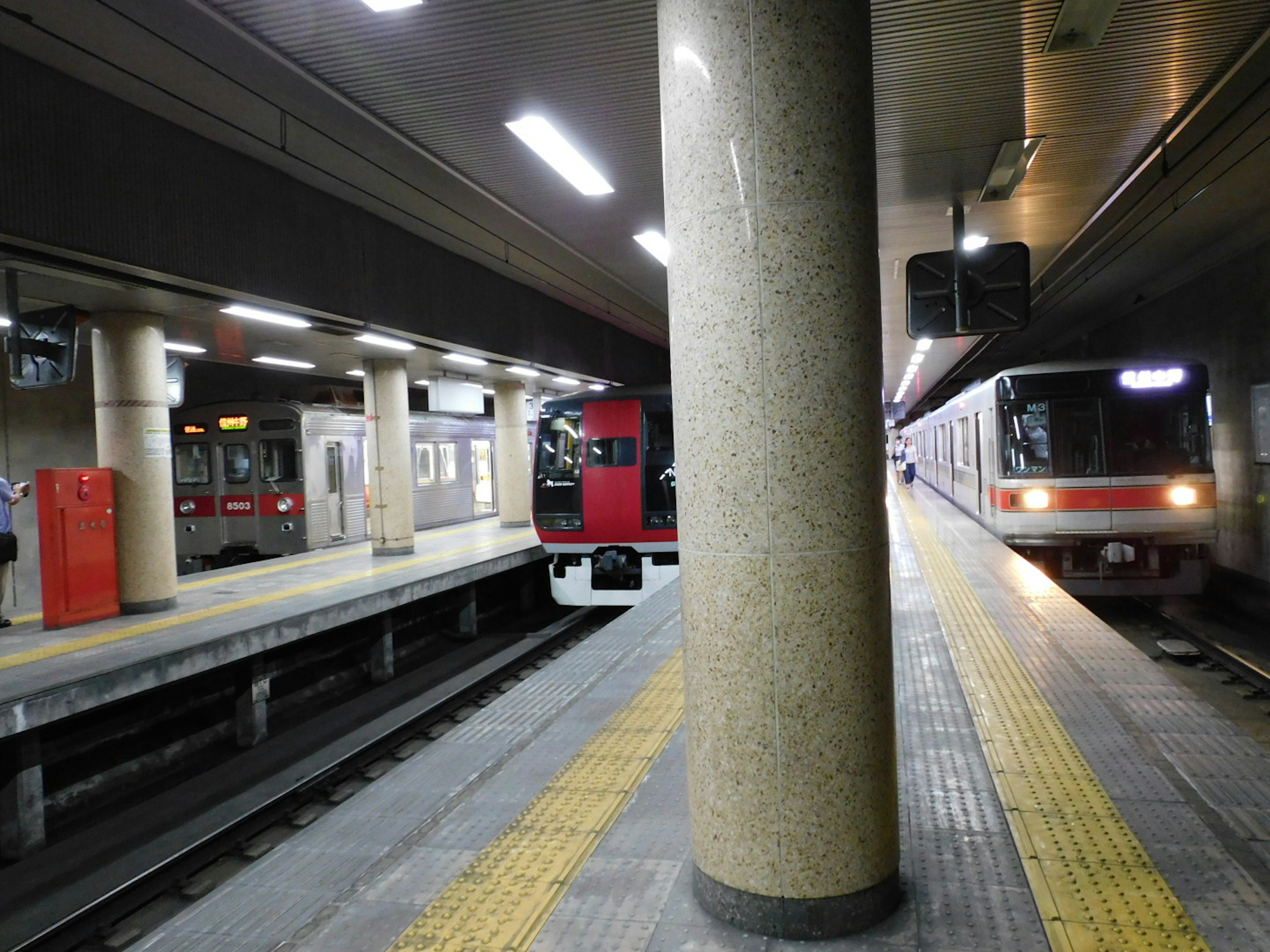 Piattaforma della stazione della metropolitana con un treno rosso e un treno bianco