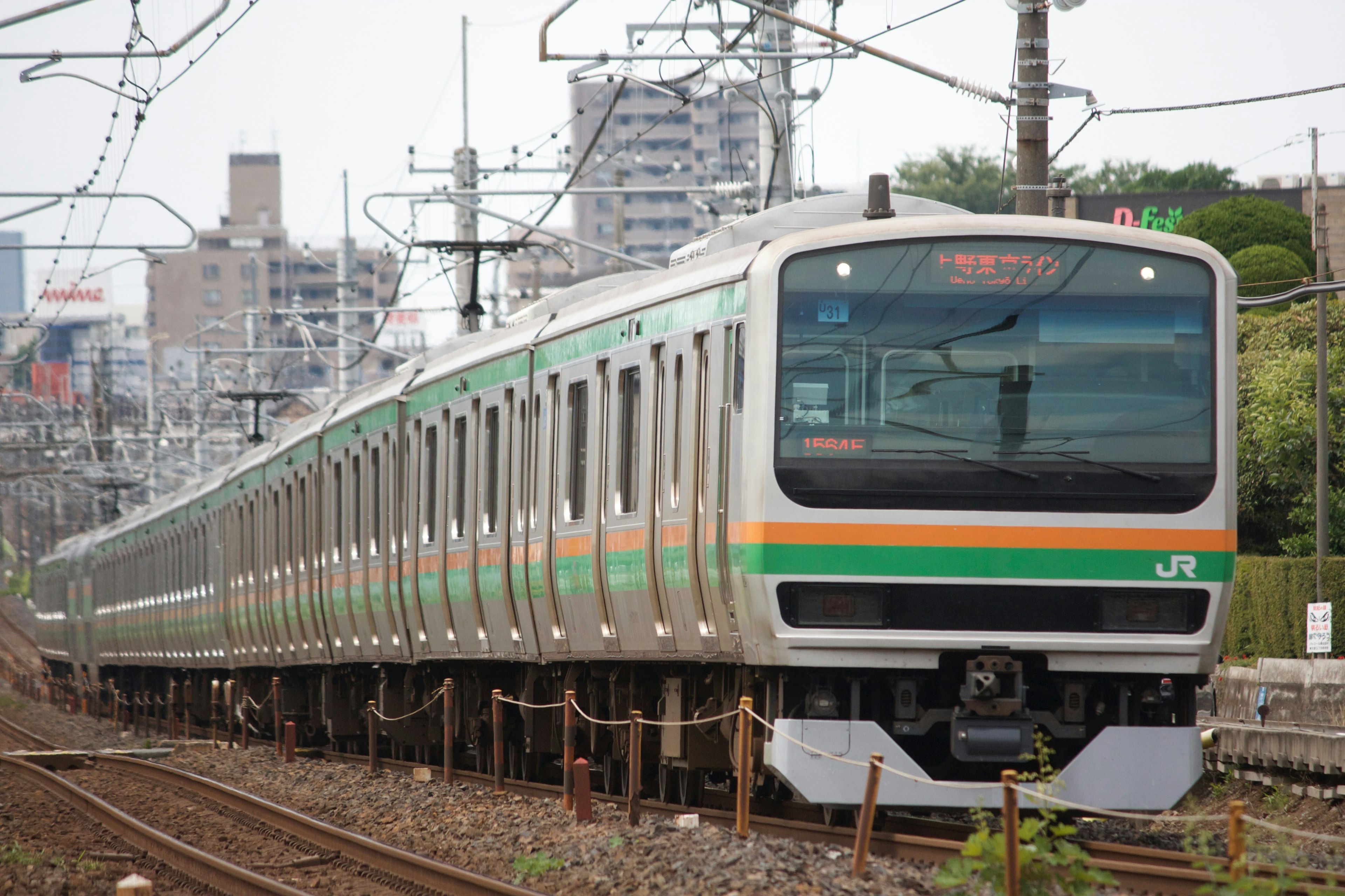 Un tren japonés con rayas verdes y naranjas en movimiento