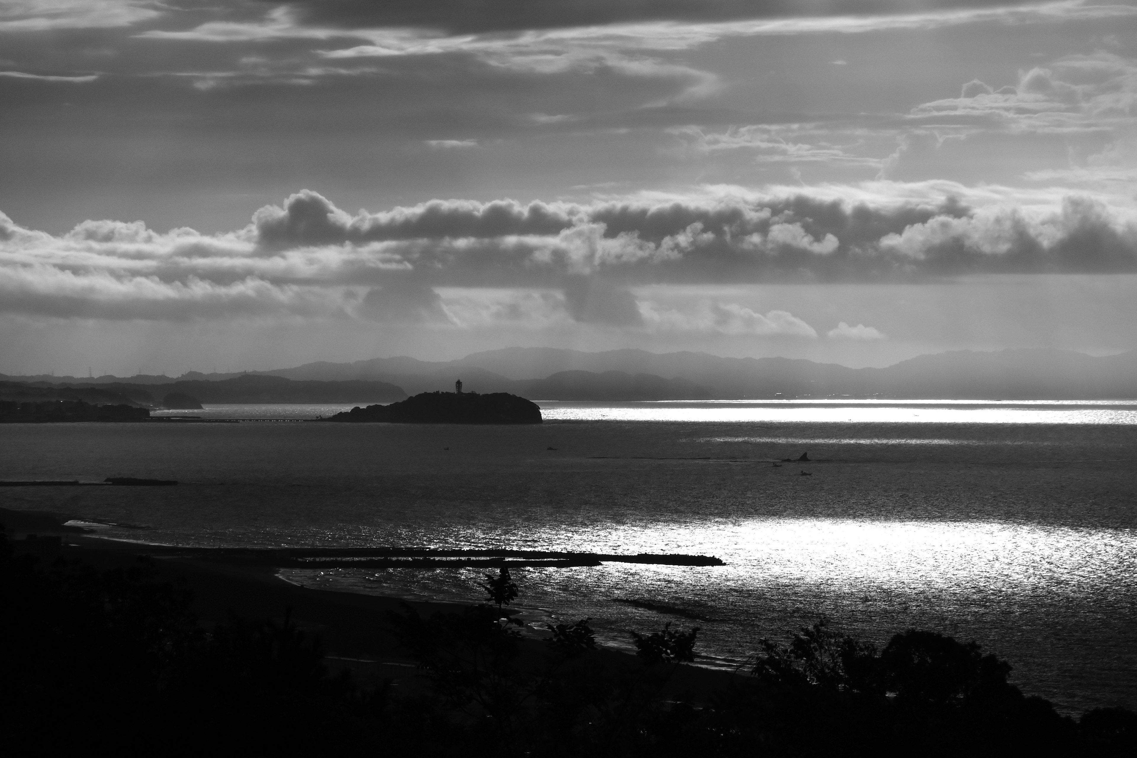 Black and white seascape featuring an island and a lighthouse