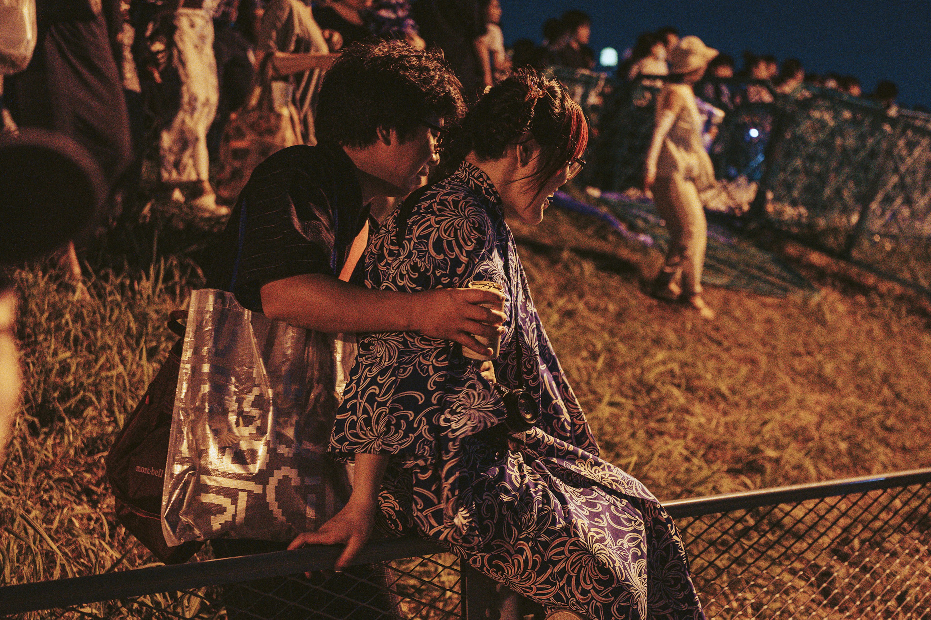 Una pareja en ropa tradicional sentada junta en un festival nocturno