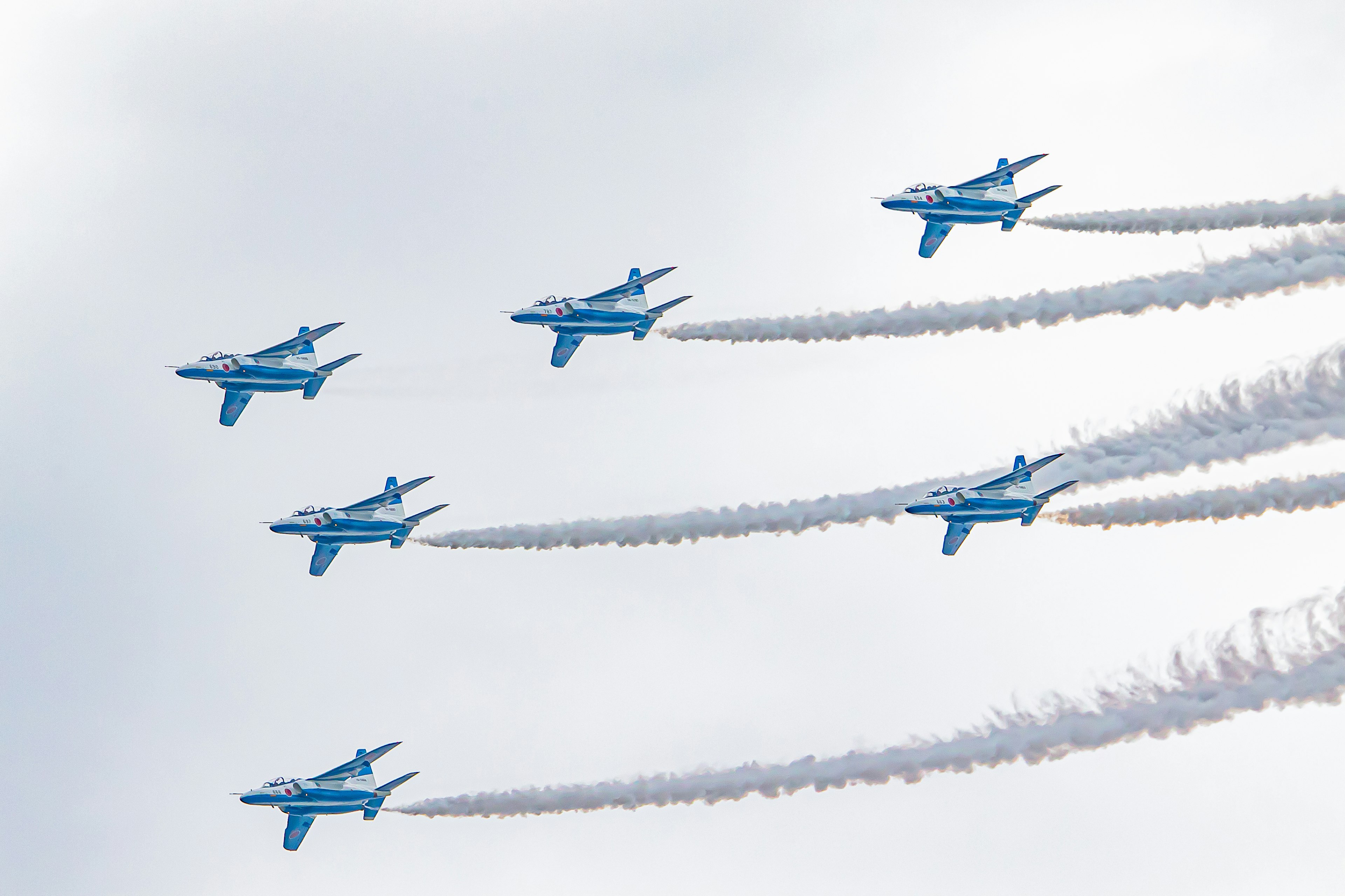 Blue aircraft performing aerial maneuvers with smoke trails