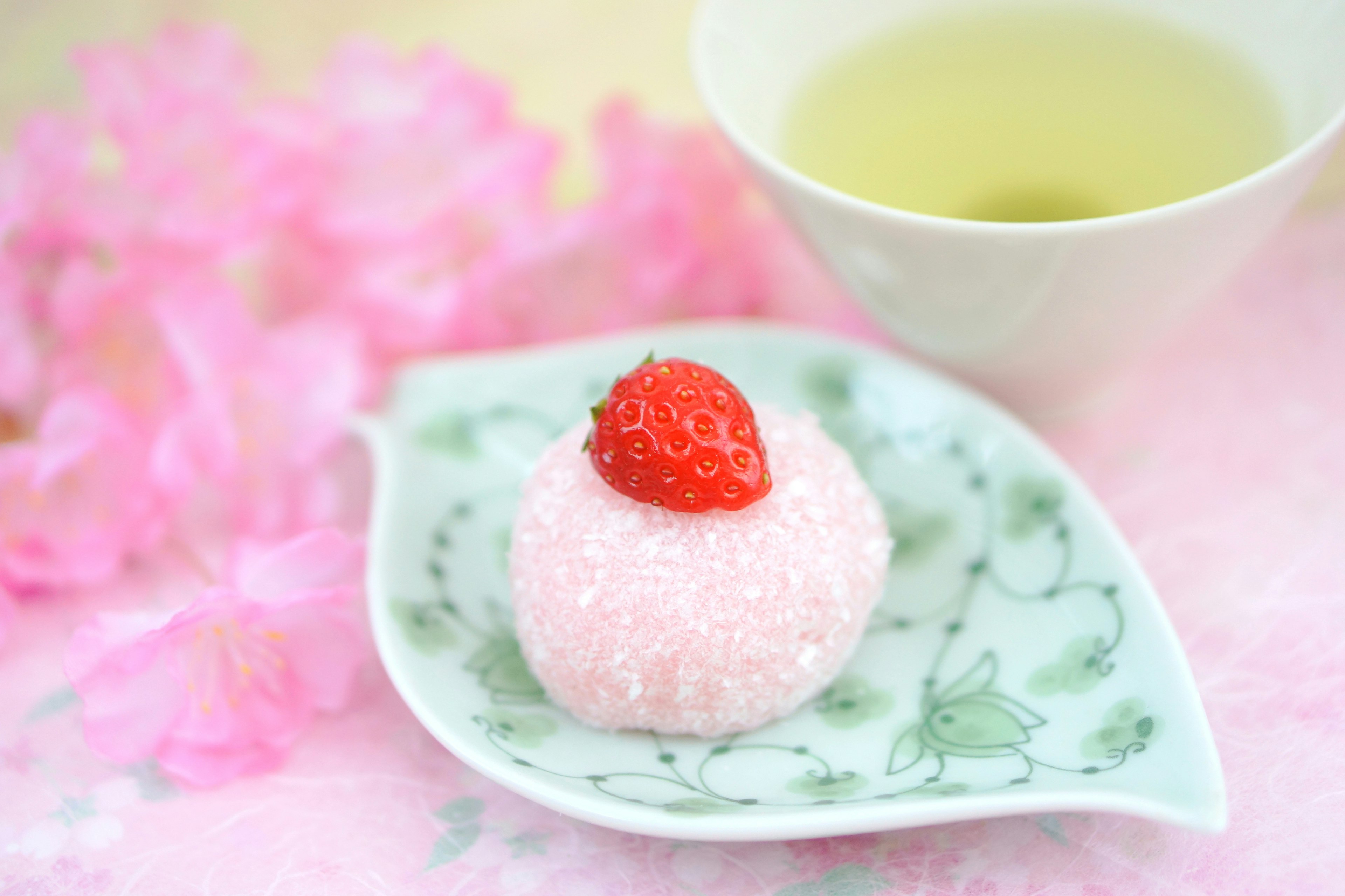 Strawberry topped Japanese sweet on a leaf plate with green tea