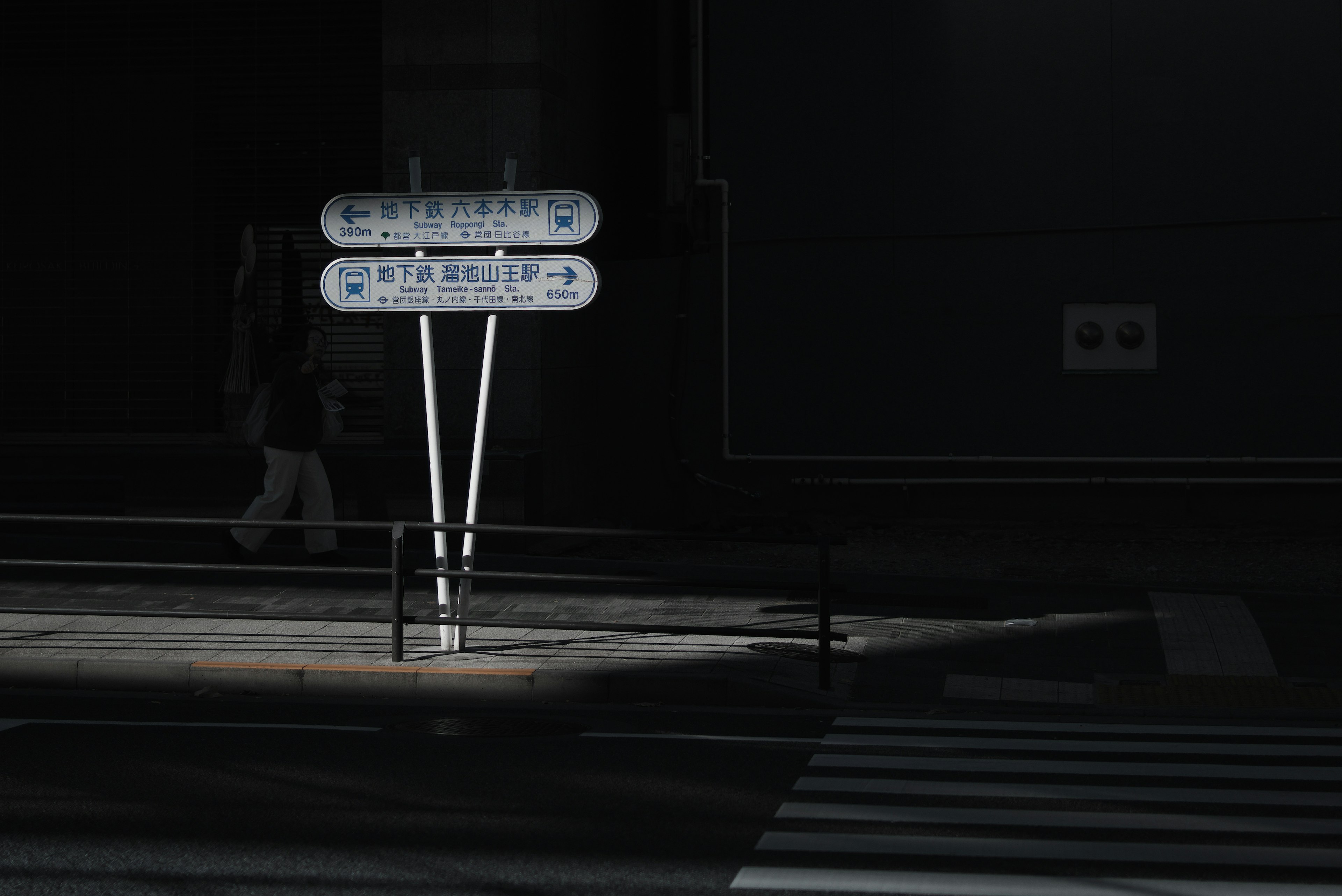 Straßenschilder im schwachen Licht mit der Silhouette eines Passanten