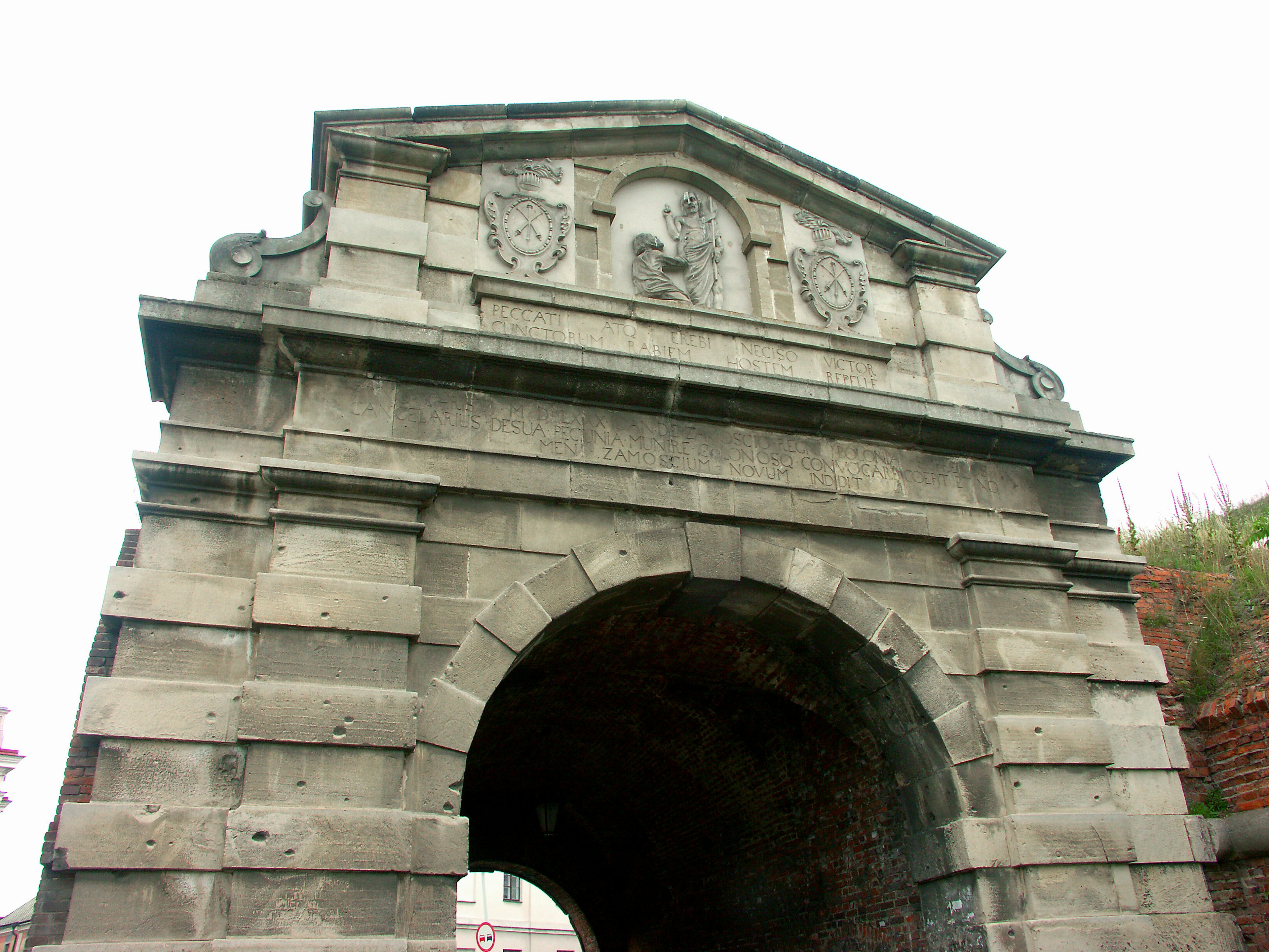 Antico arco di pietra in rovina con stemmi scolpiti in cima