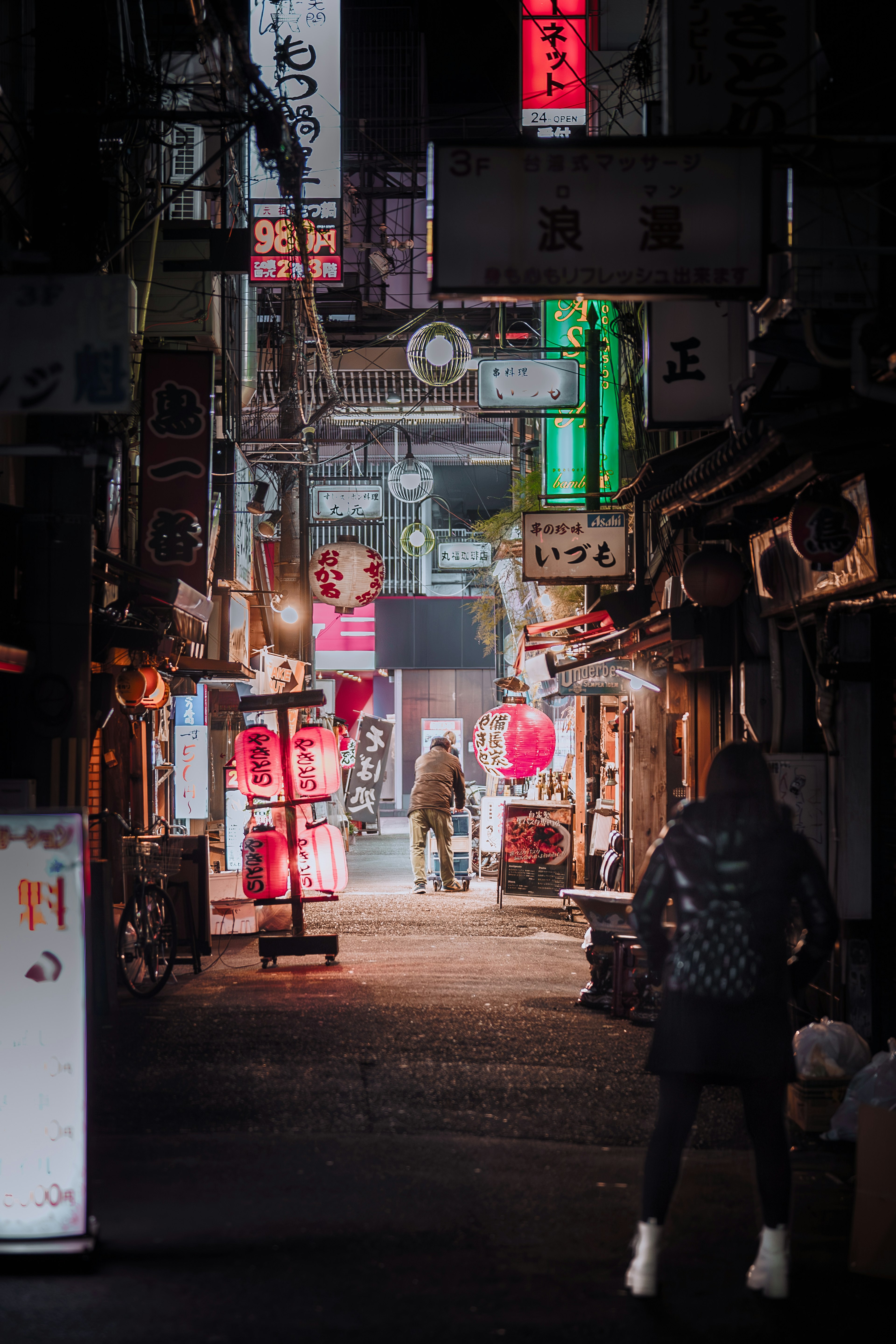 Calle animada de noche con letreros de neón y una persona caminando