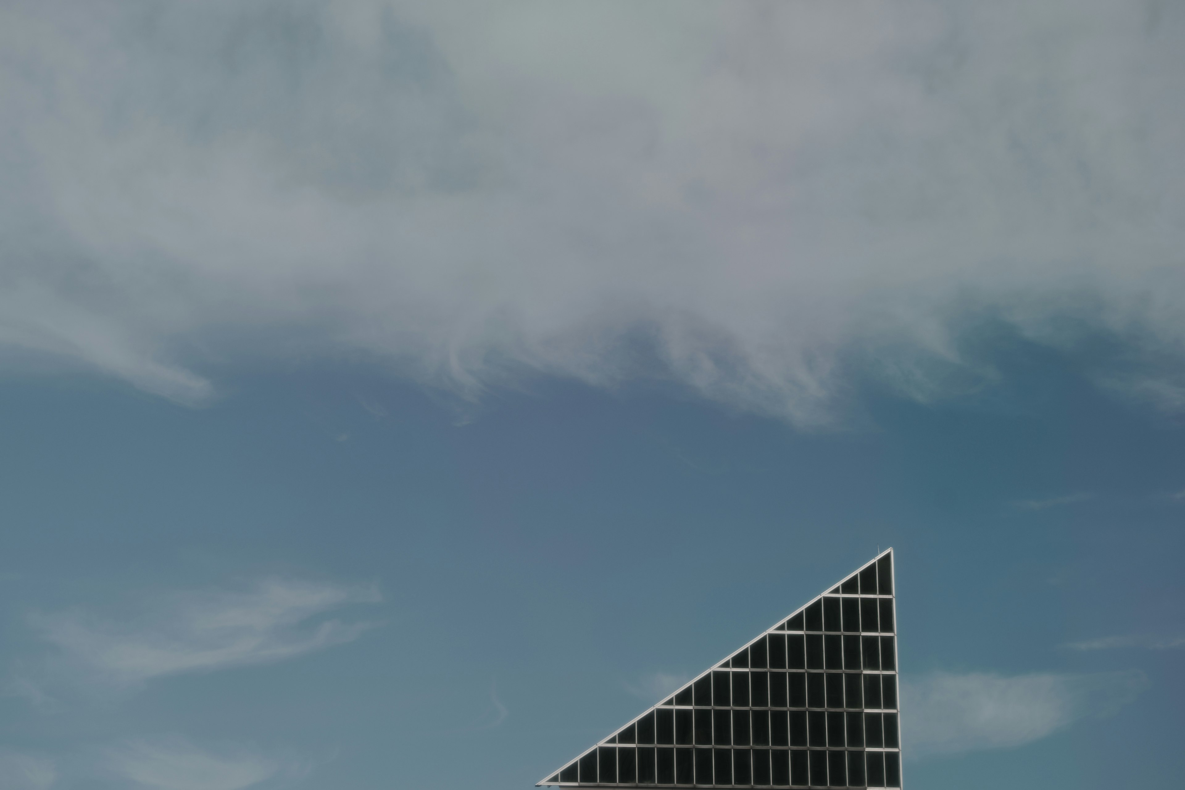 Modern triangular building partially visible against a blue sky