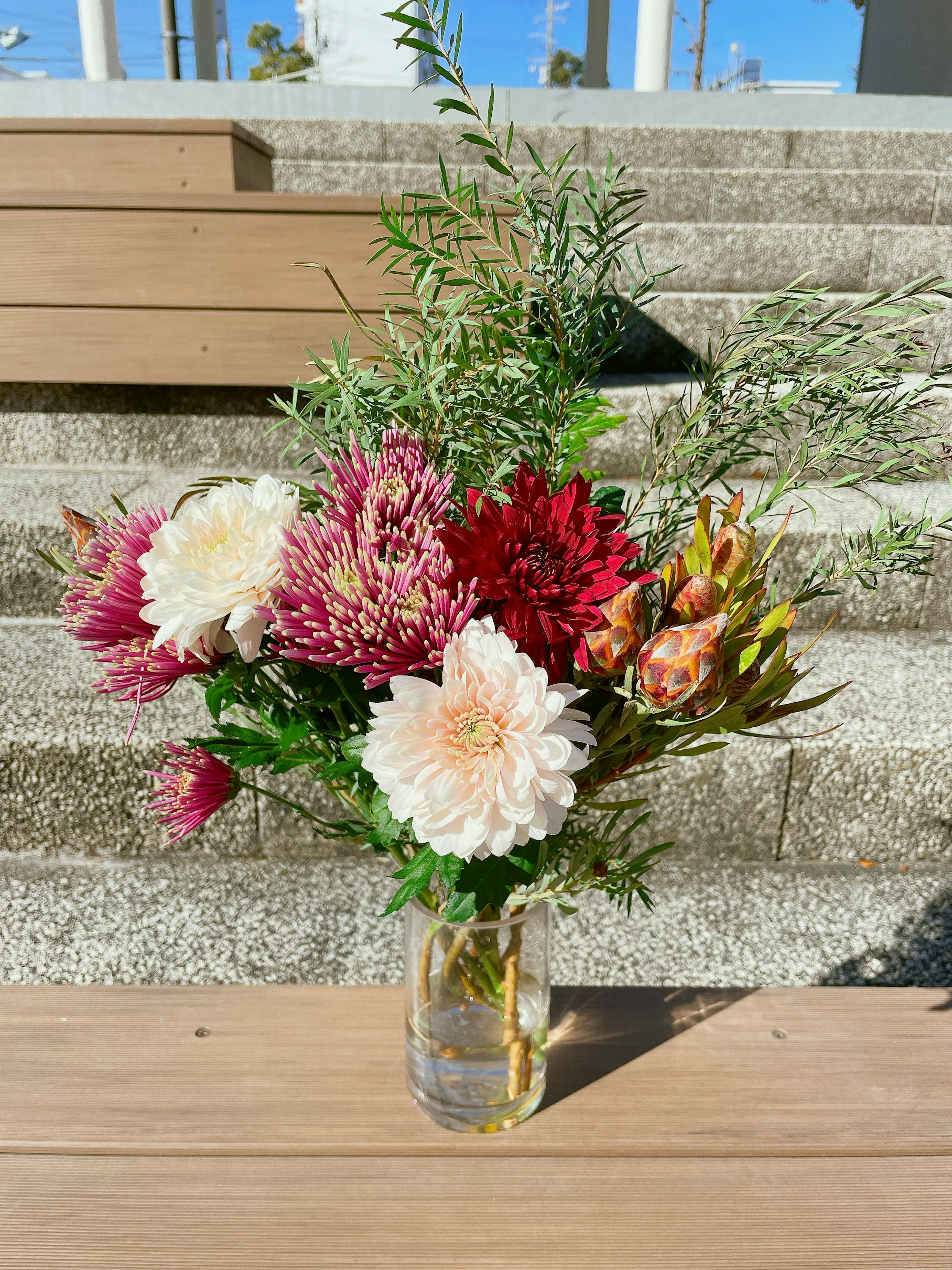 Un bouquet de fleurs colorées dans un vase en verre sur une table en bois