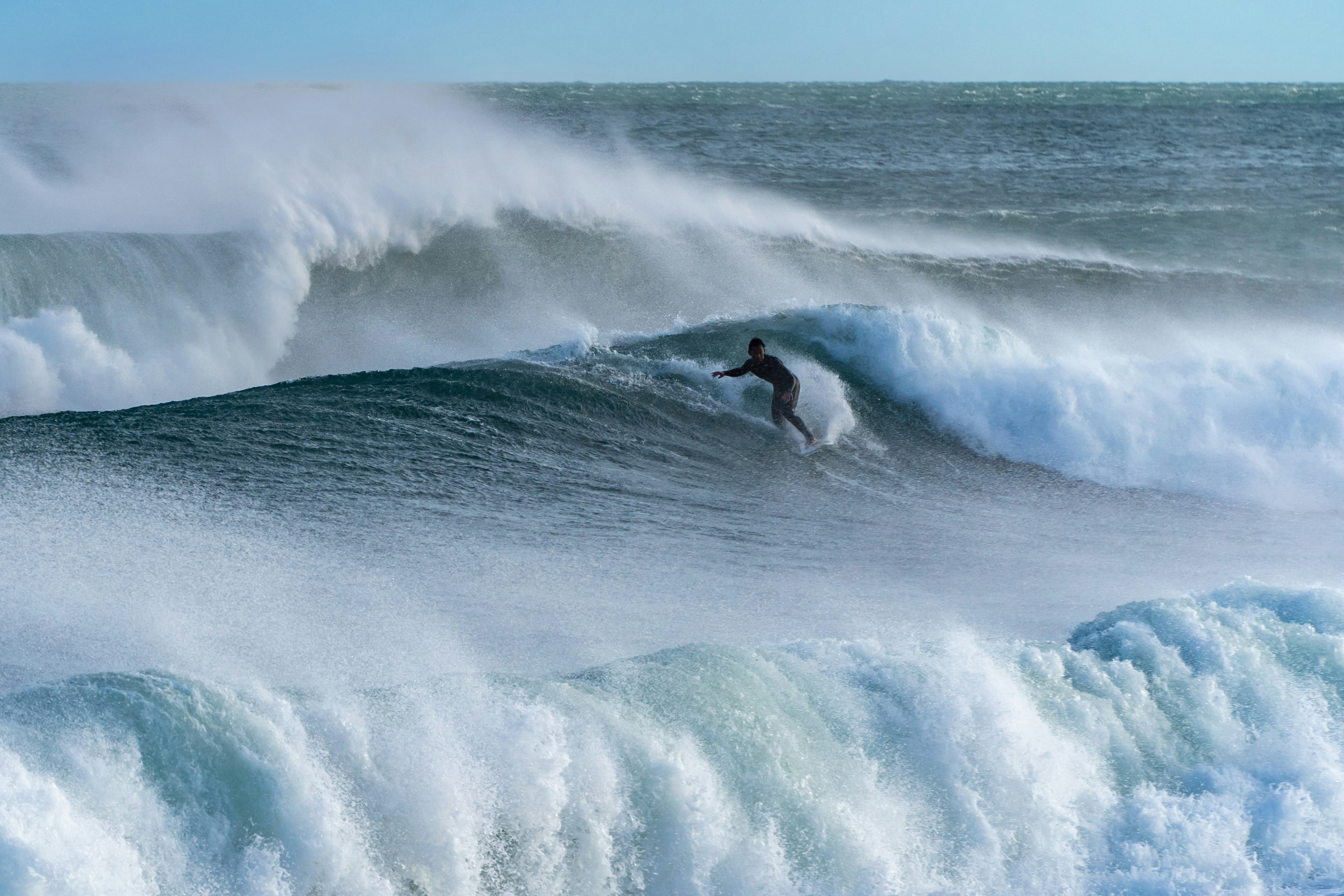 Surfer reitet auf einer Welle mit blauem Ozean und weißem Spritzwasser