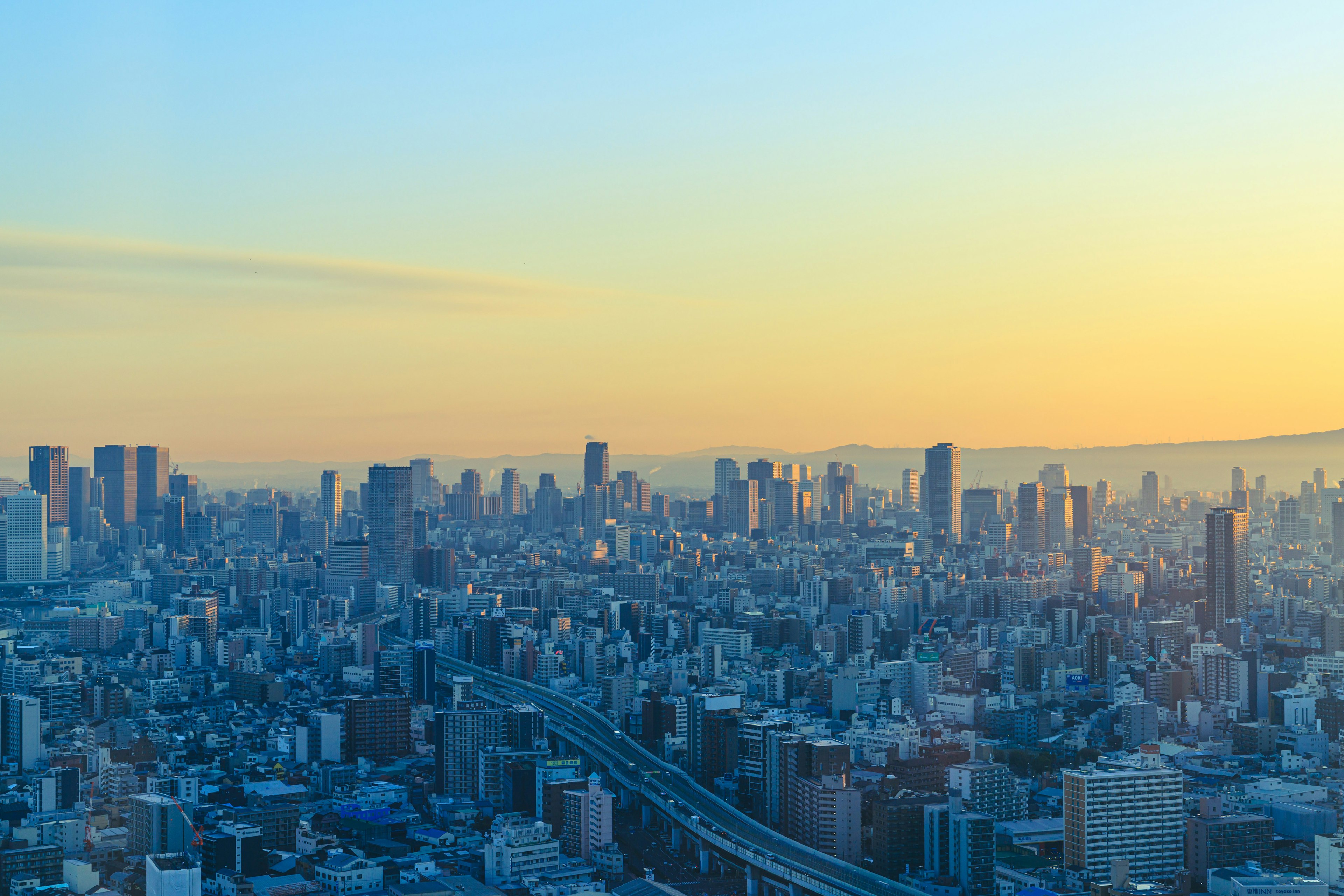 Pemandangan kota Osaka saat matahari terbenam dengan gedung pencakar langit dan langit cerah