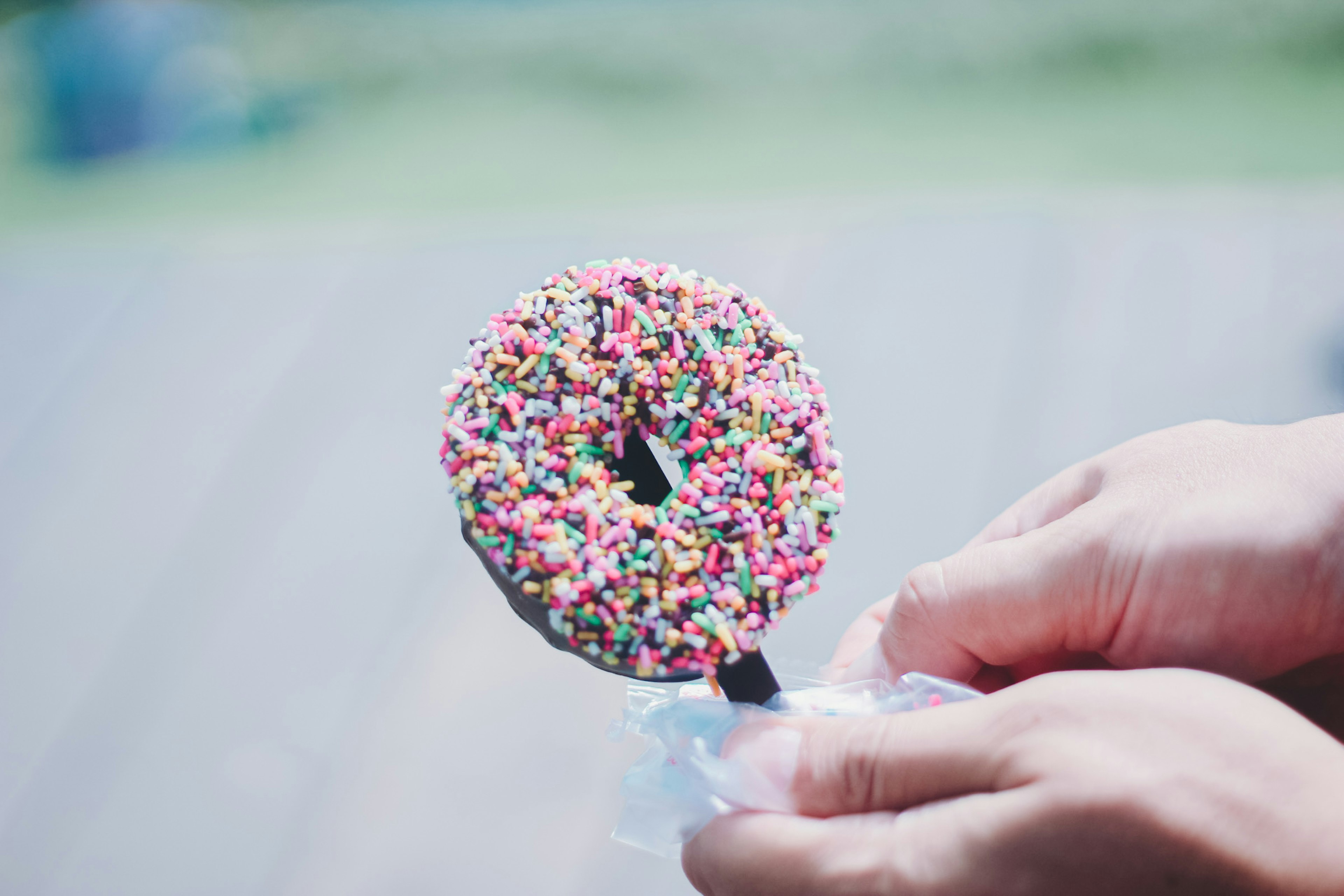 Una persona che tiene un donut con sprinkles colorati