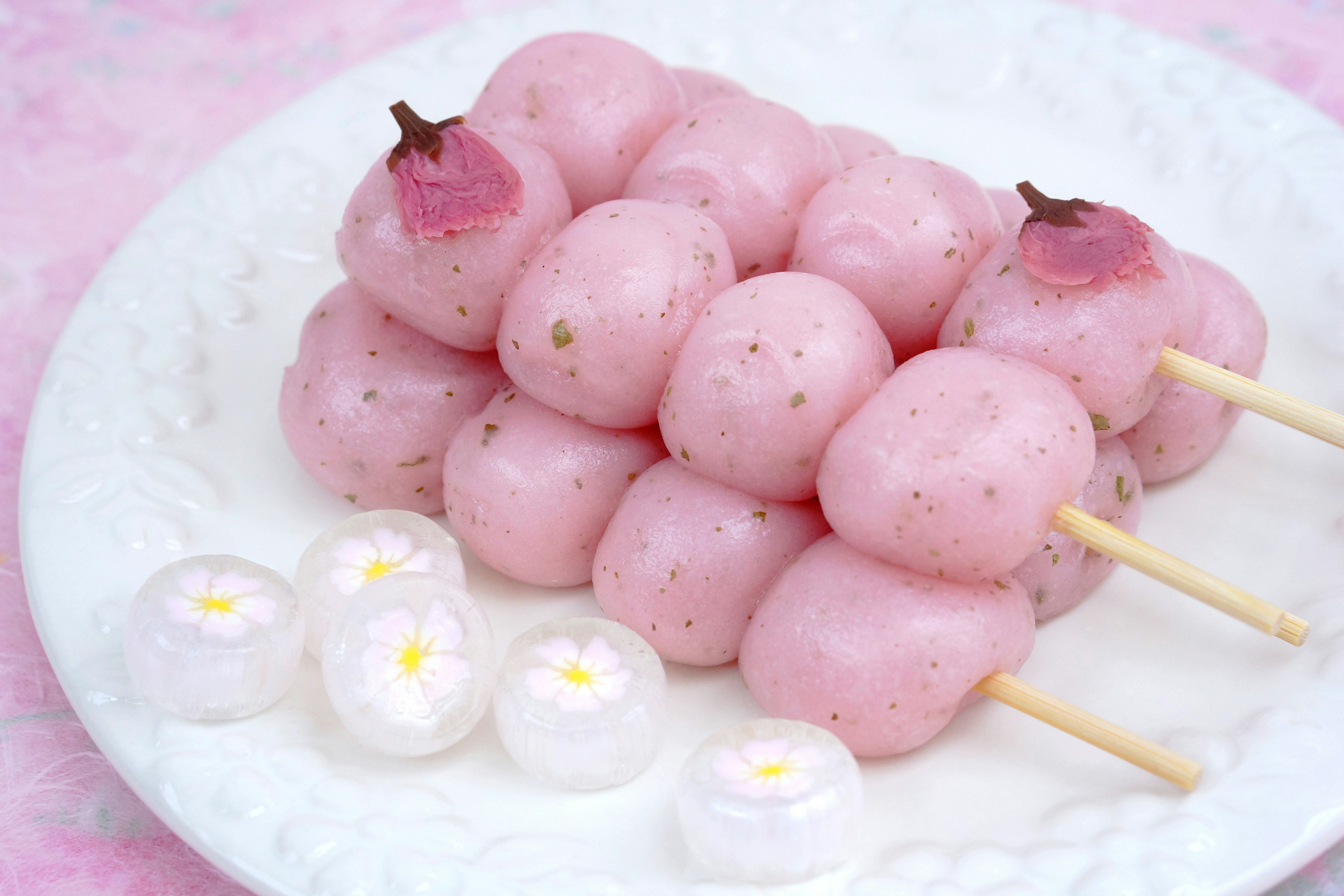 Dumpling berwarna pink lembut ditusuk pada batang disajikan di piring