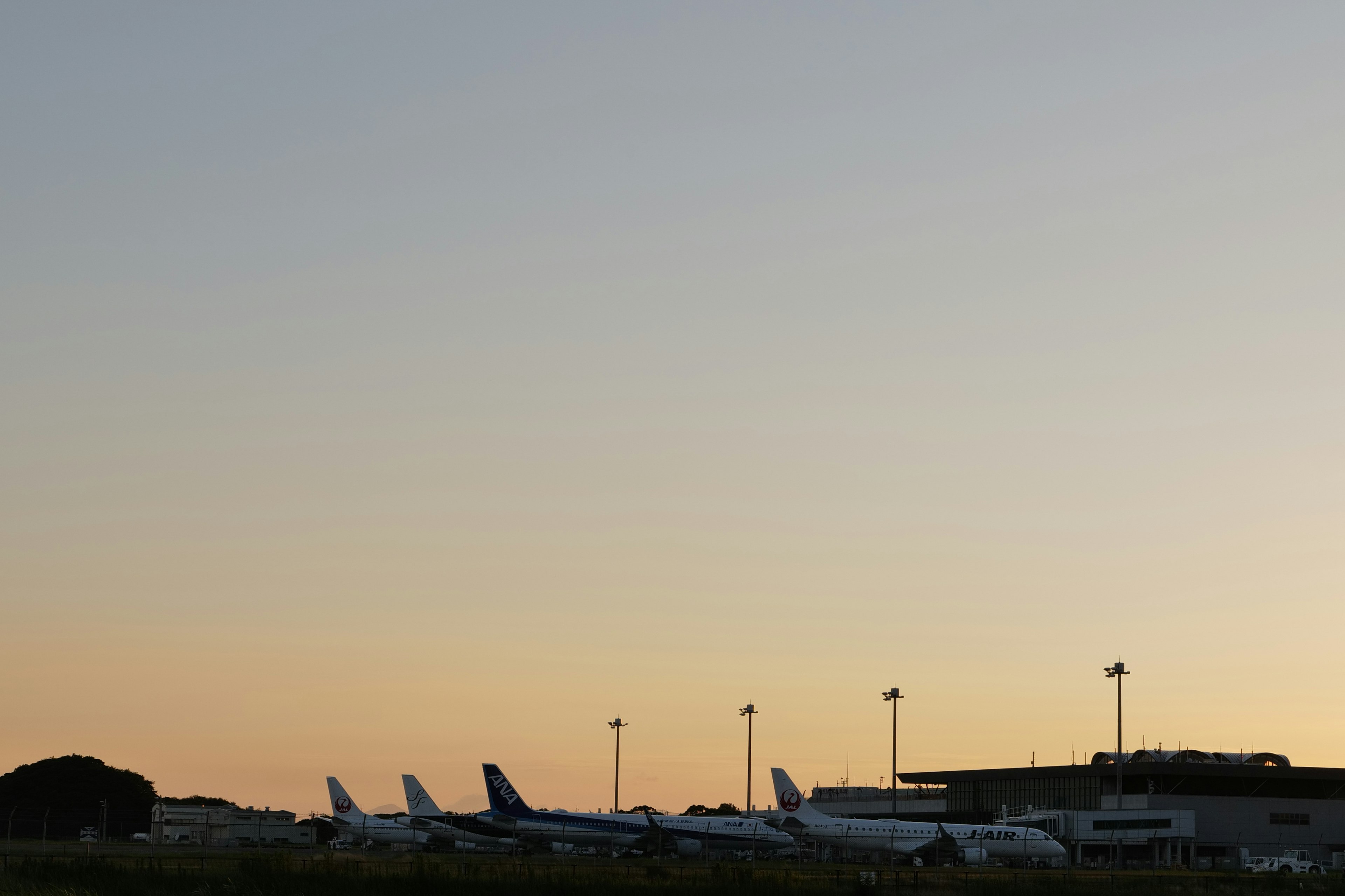 夕焼けの空を背景に並ぶ航空機と空港のターミナル