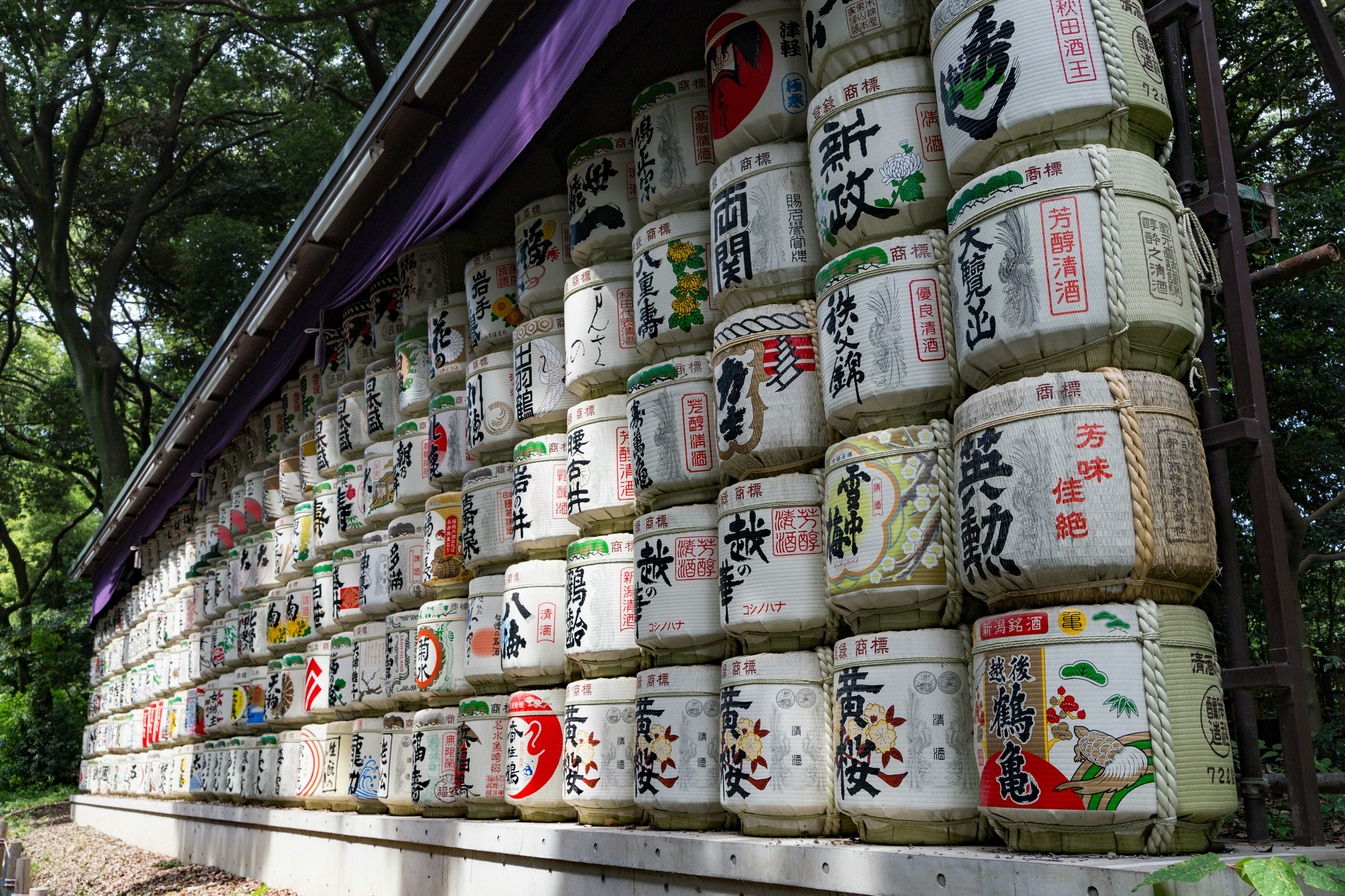 A scenic view of Japanese sake barrels arranged in a wall, featuring colorful labels and decorations