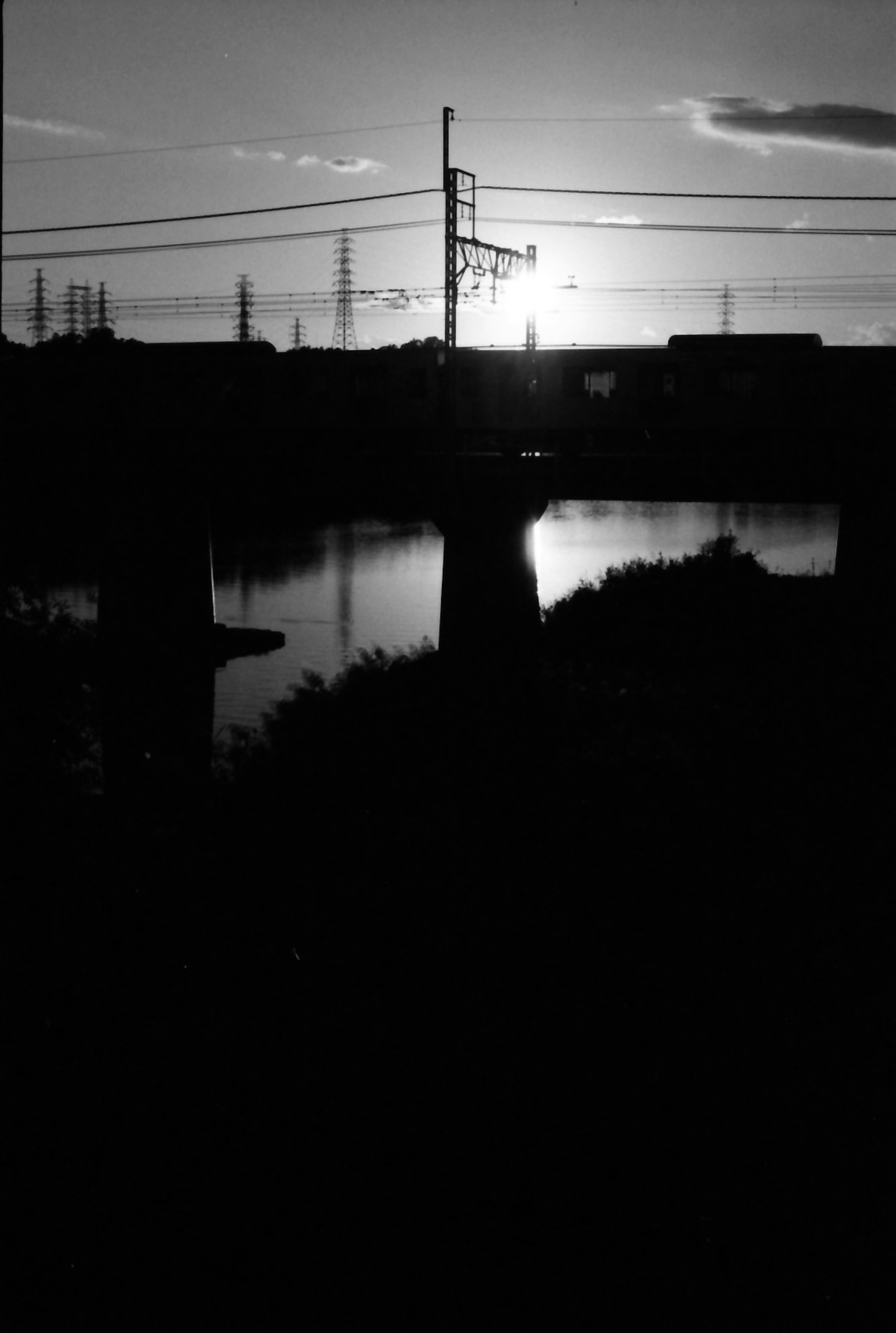 Río reflejando el atardecer con líneas eléctricas en silueta