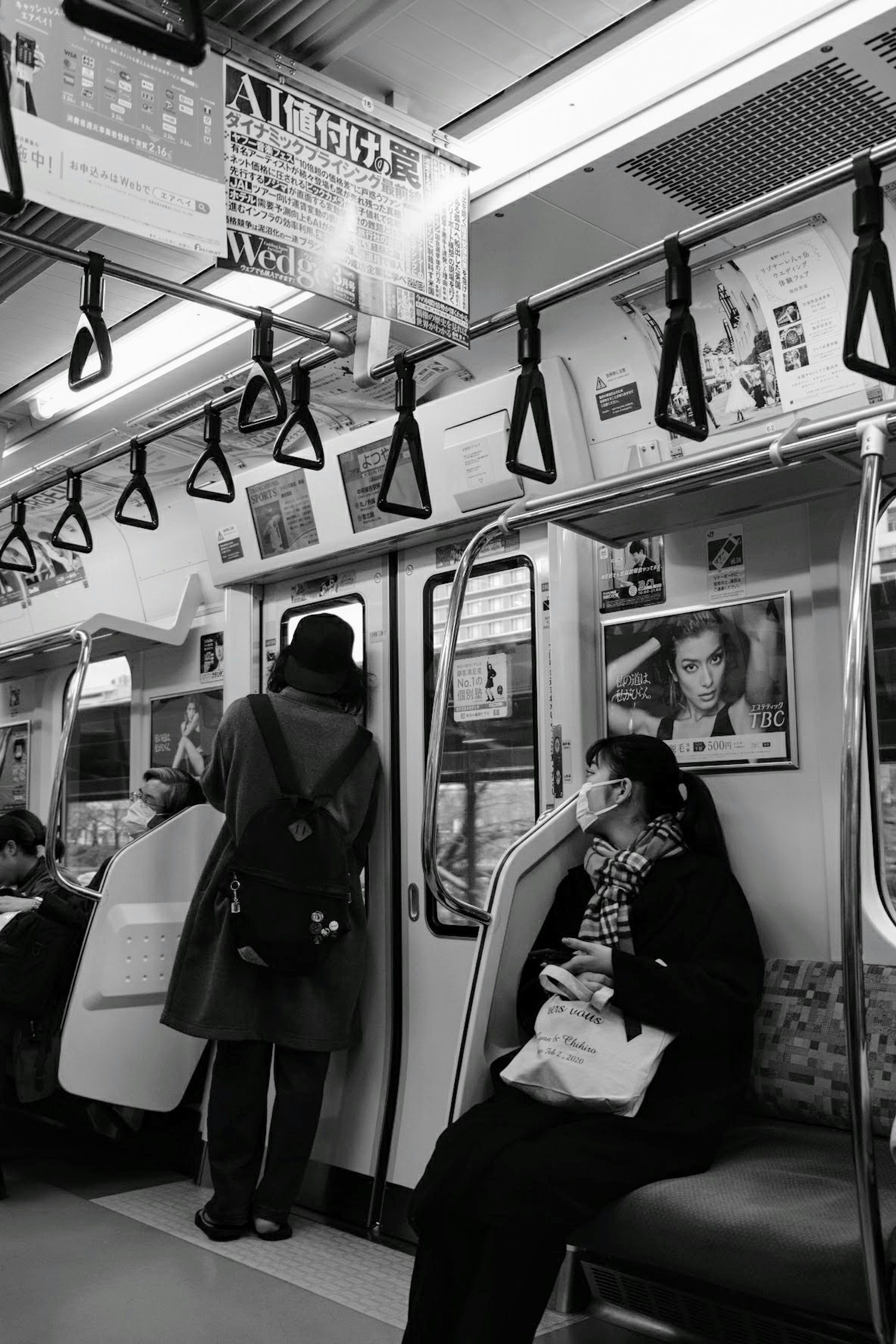 Interno di una metropolitana in bianco e nero con passeggeri e maniglie visibili