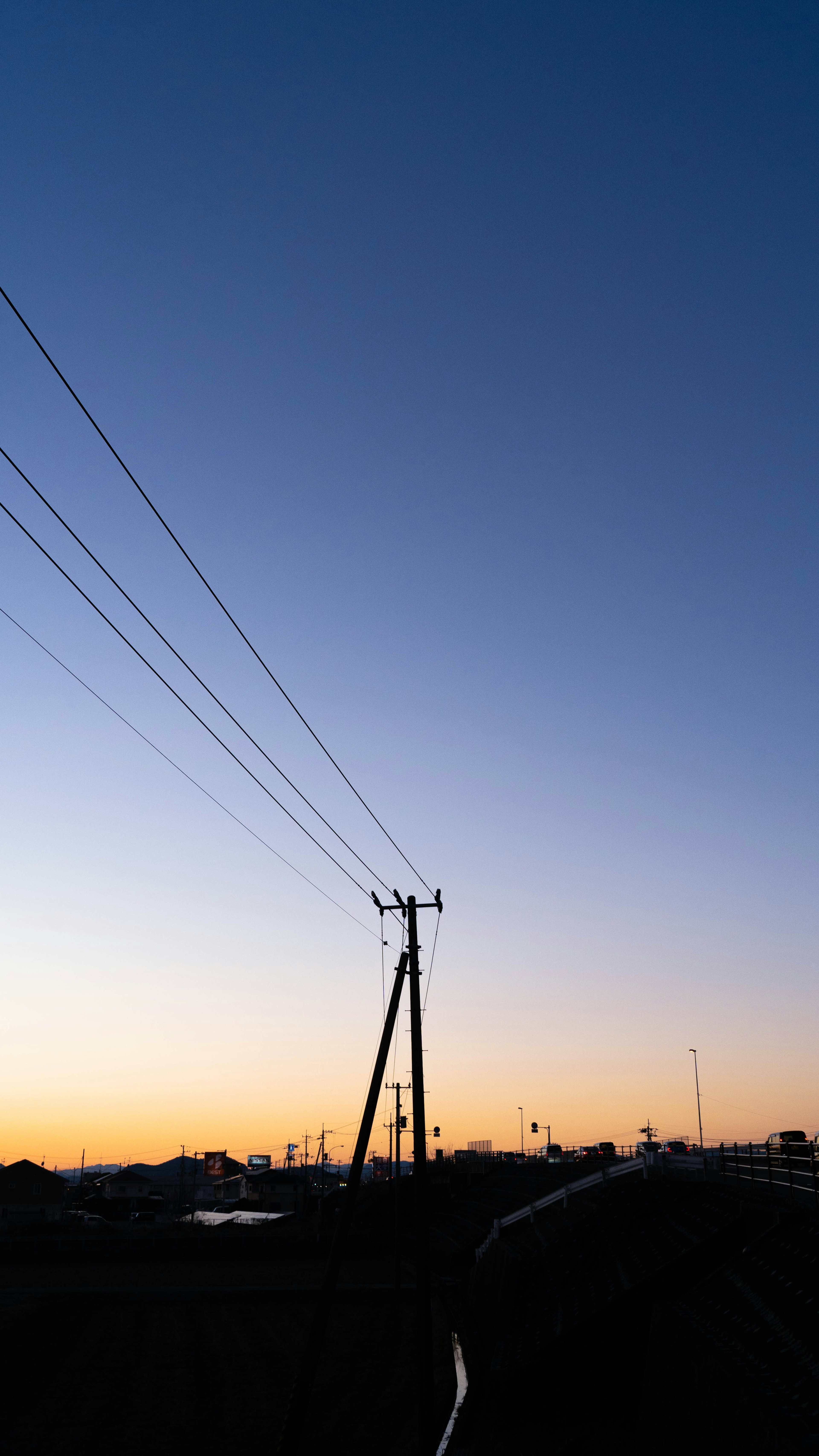 夕暮れ時の電柱と電線のシルエットが映える風景