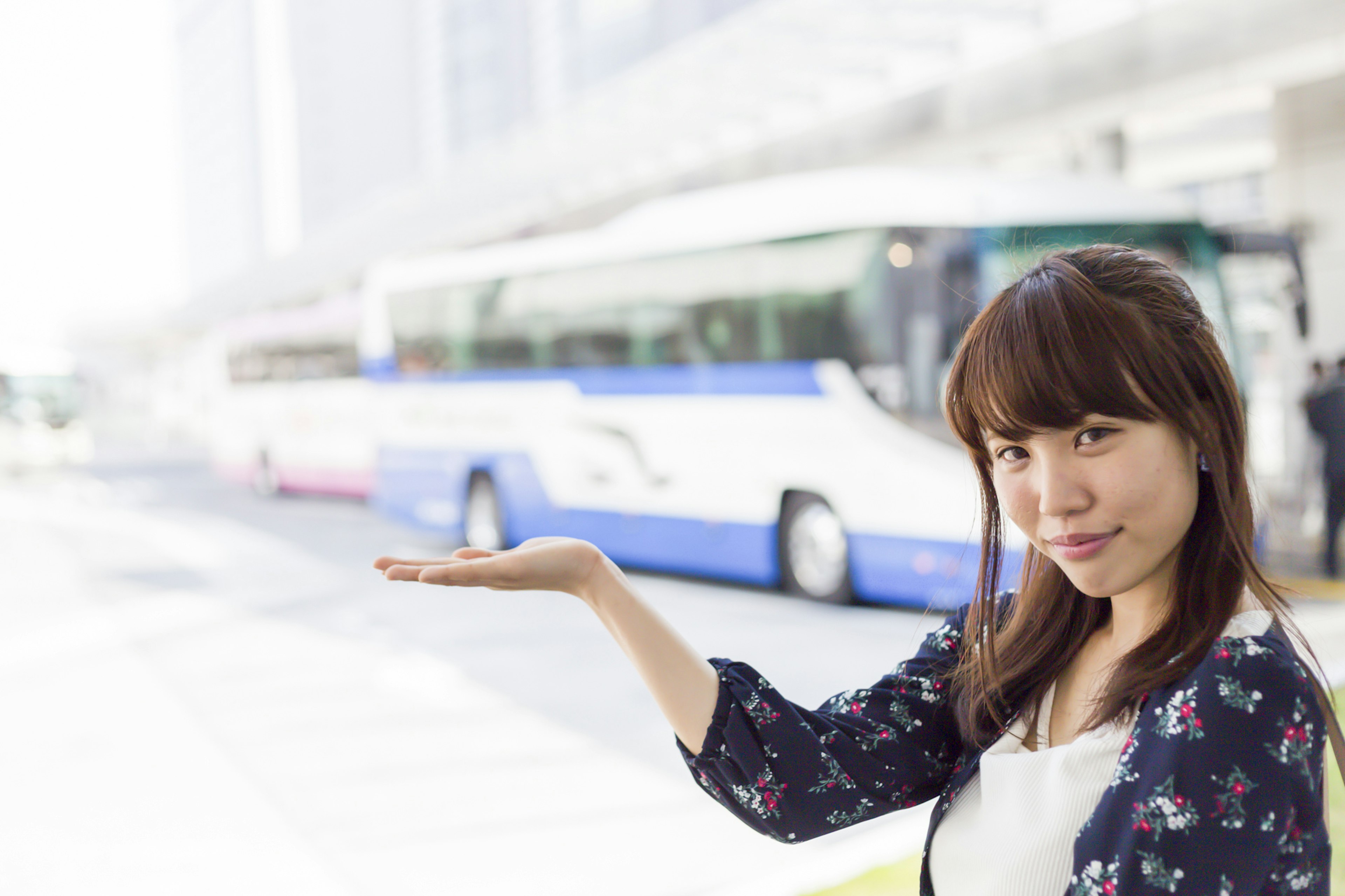 Woman gesturing at a bus stop with a bus in the background