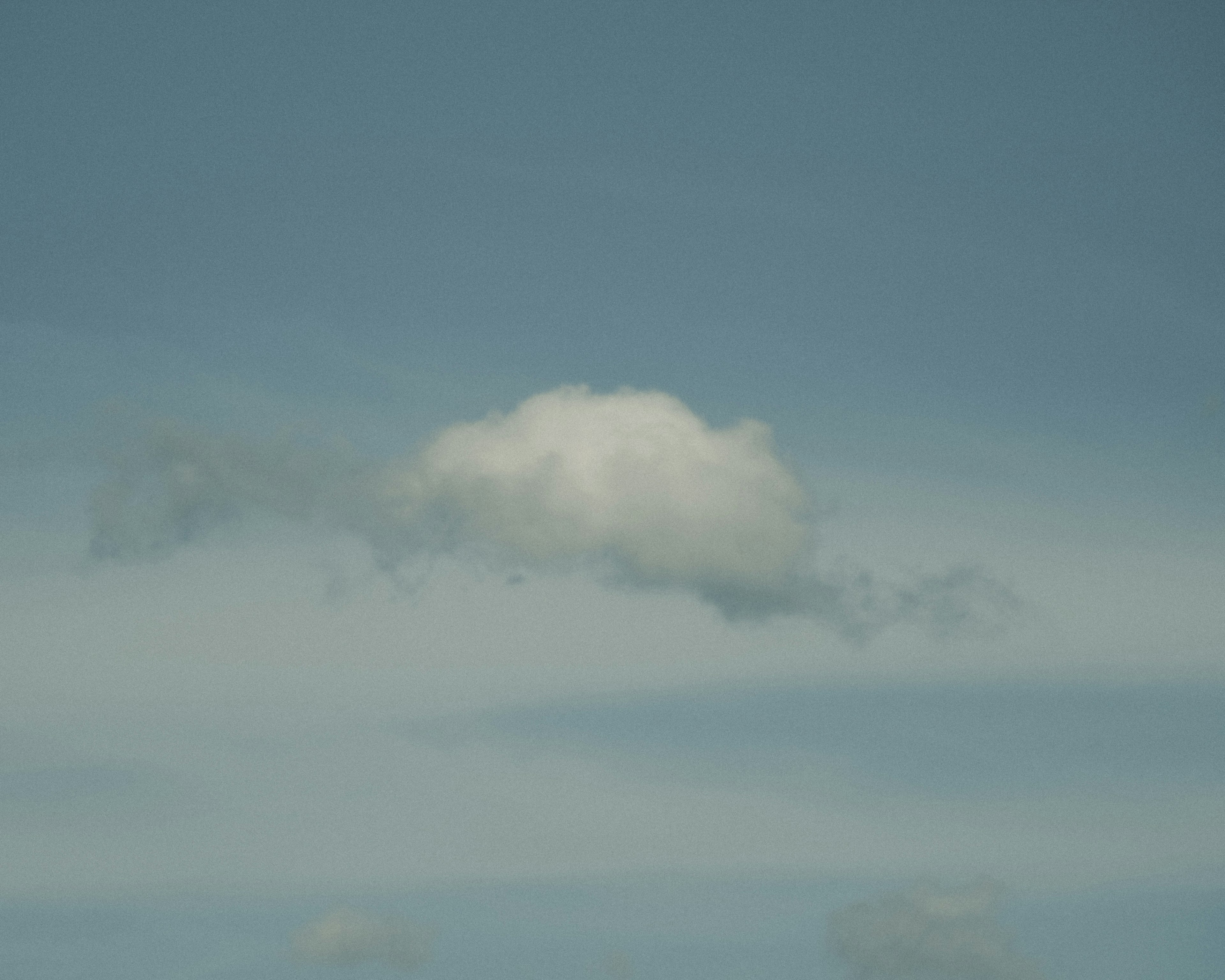 Eine einfache Ansicht einer weißen Wolke, die in einem blauen Himmel schwebt