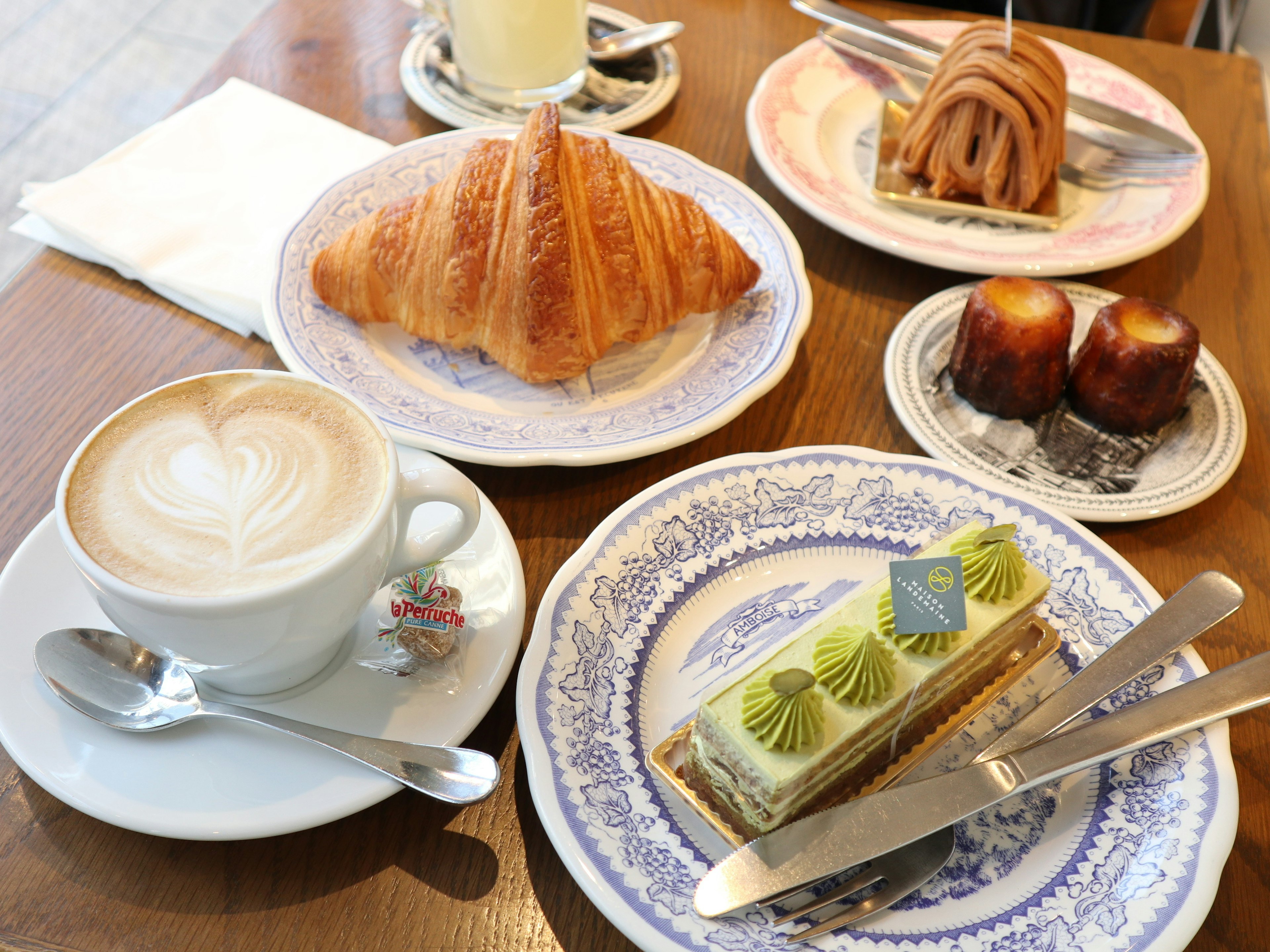 Table setting with coffee and pastries including croissant green cake and French desserts