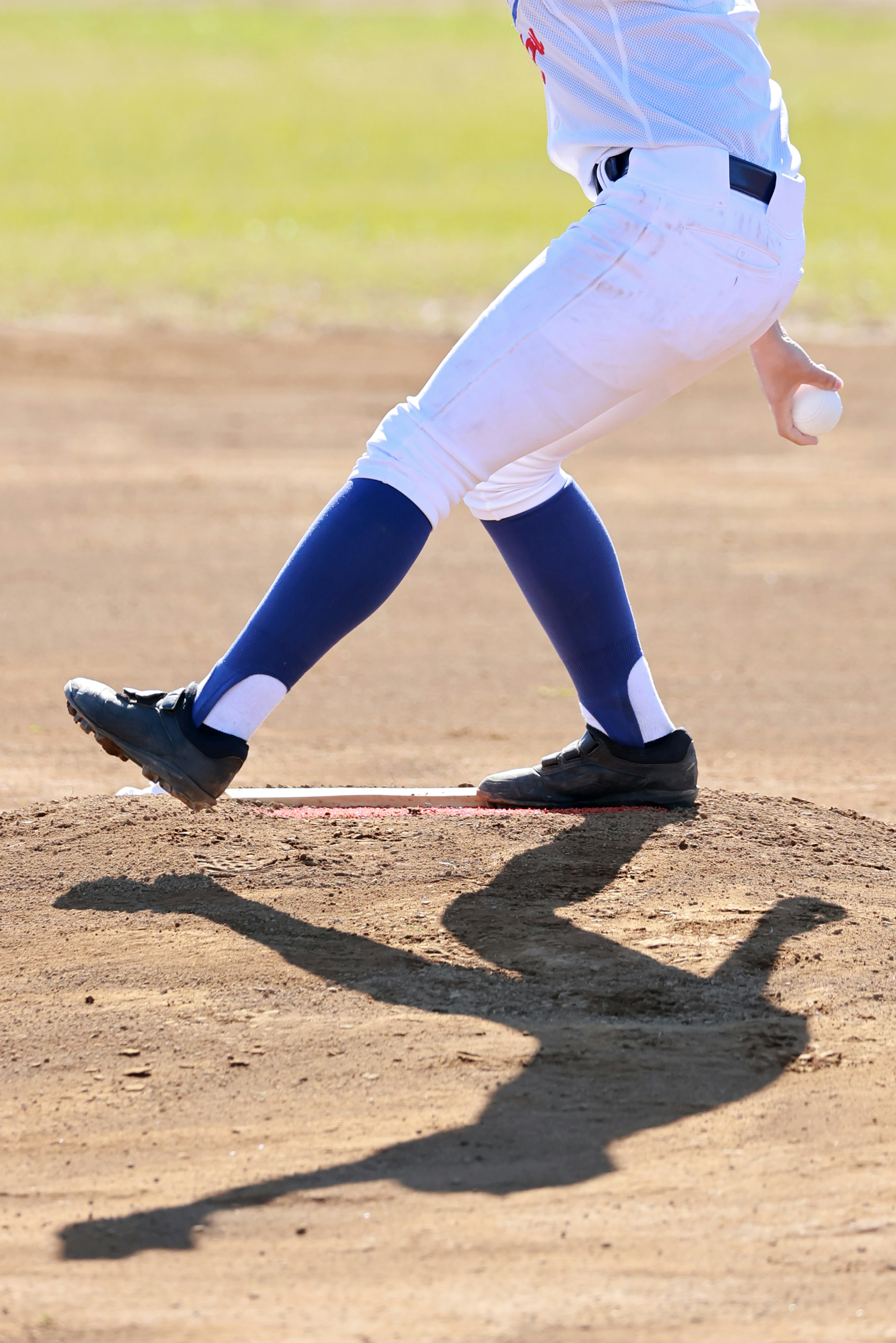 A baseball pitcher in motion on the mound throwing a ball