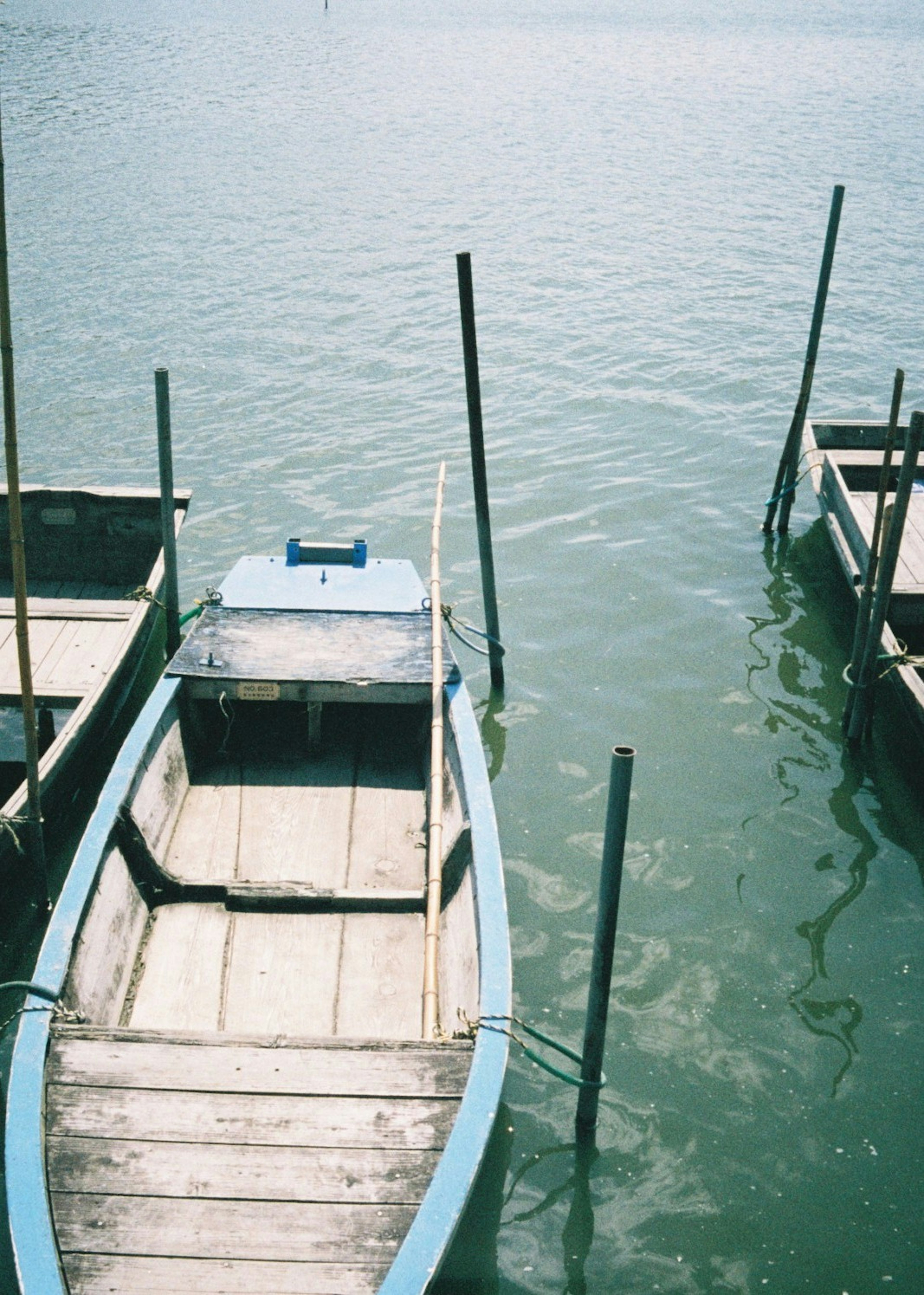 Barca blu che galleggia su acqua calma con pontili in legno