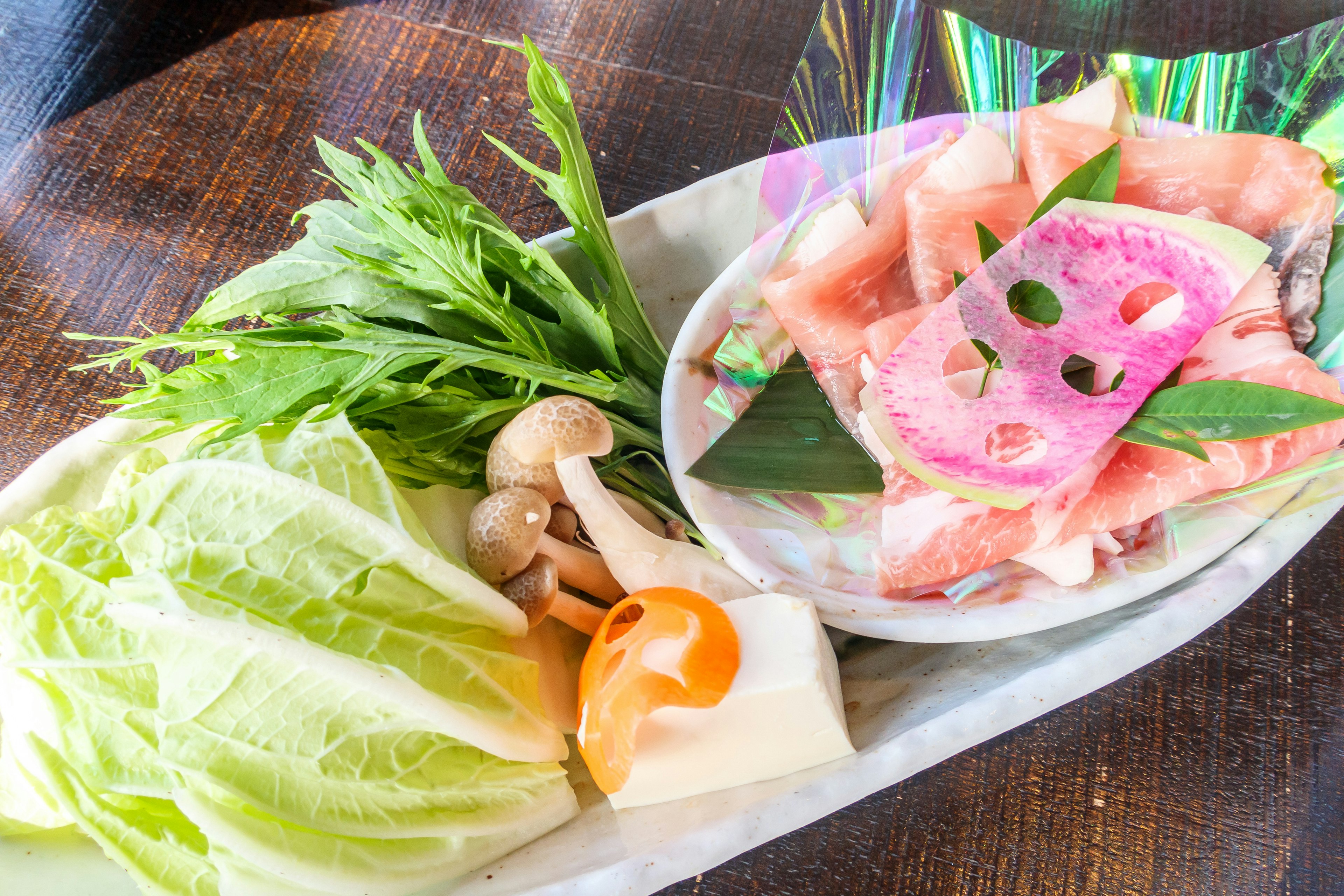 A platter of fresh vegetables and sashimi with decorative garnishes