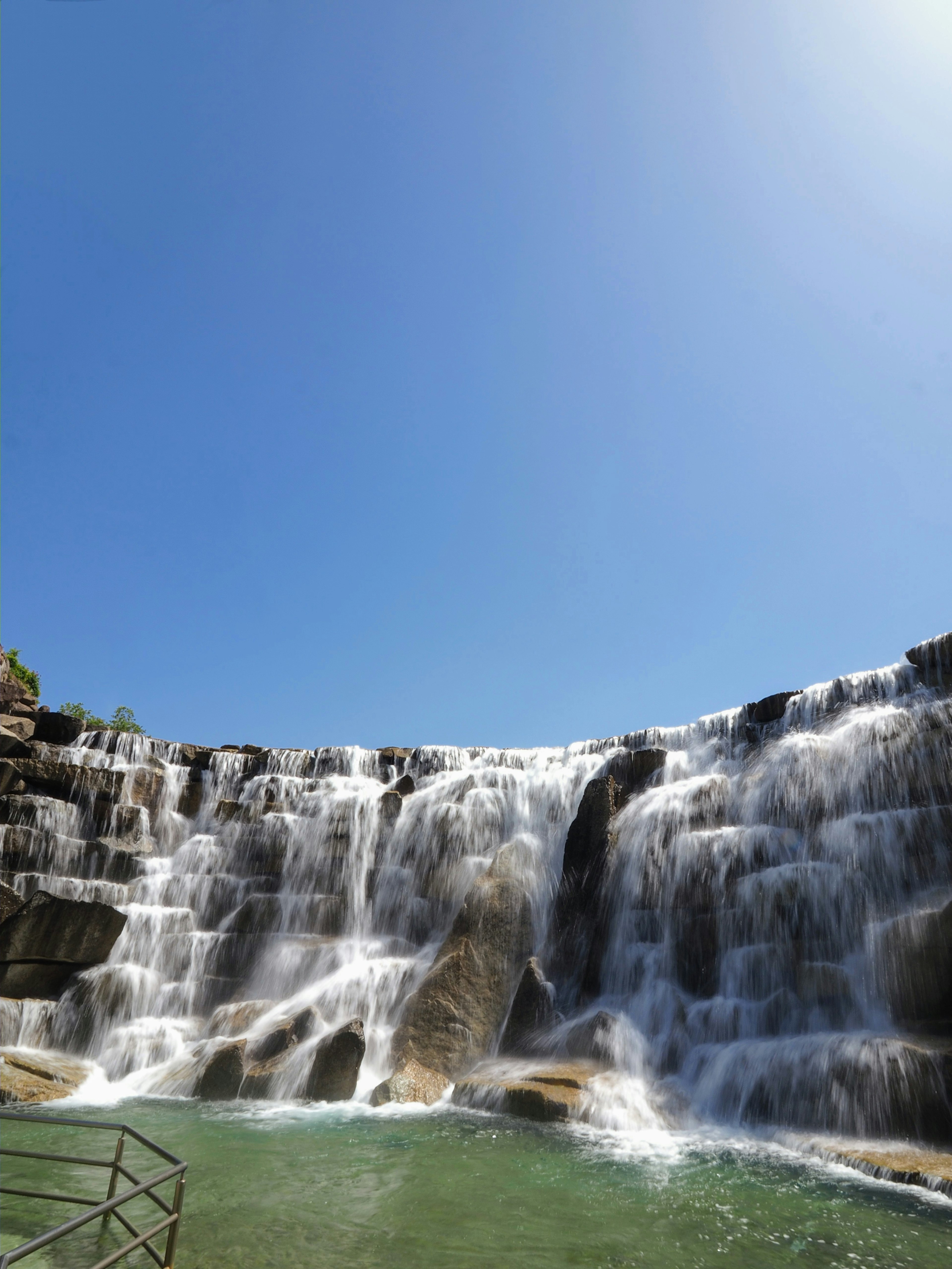 青空の下の美しい滝と緑の水面