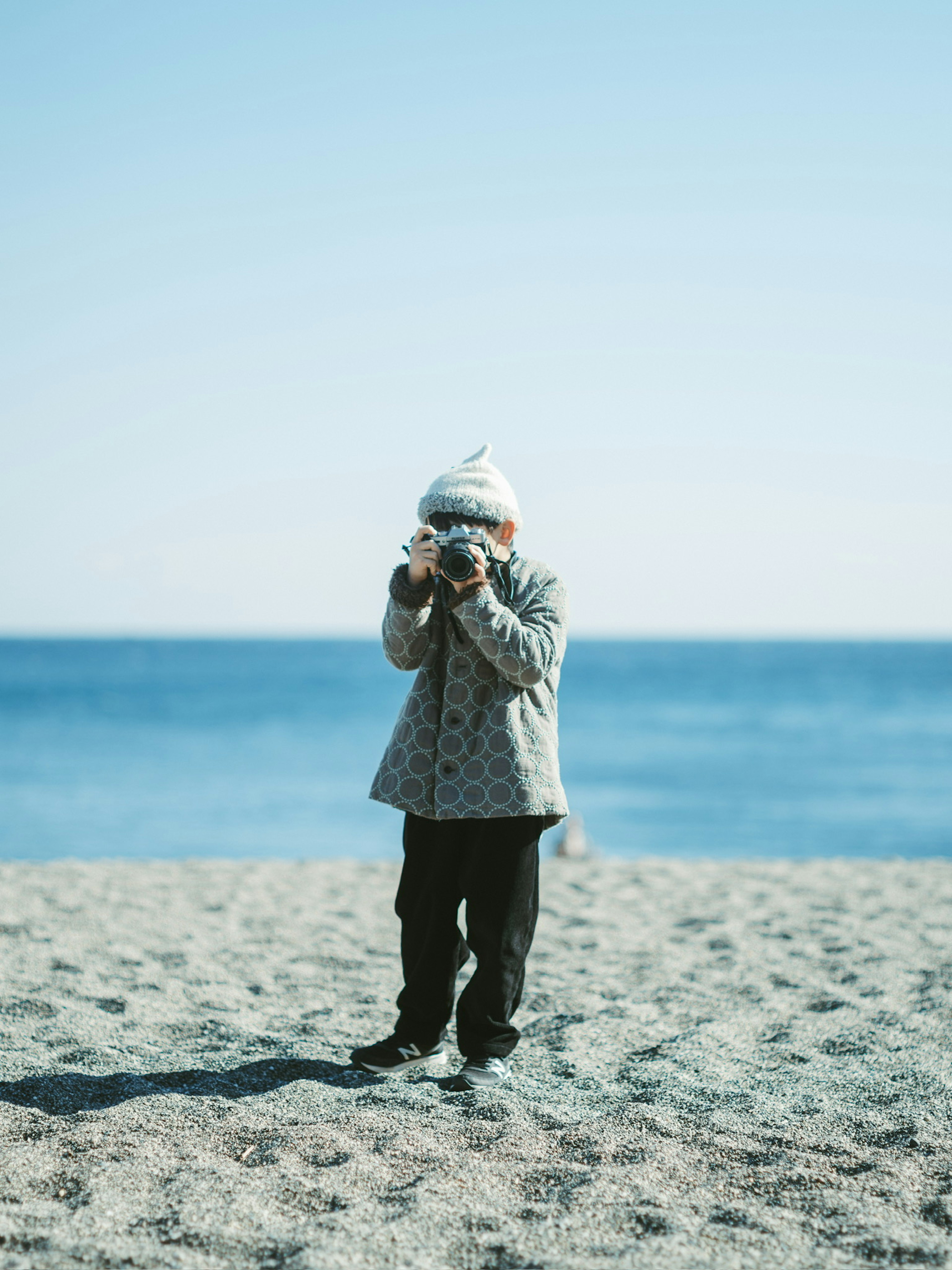 Niño sosteniendo una cámara en la playa