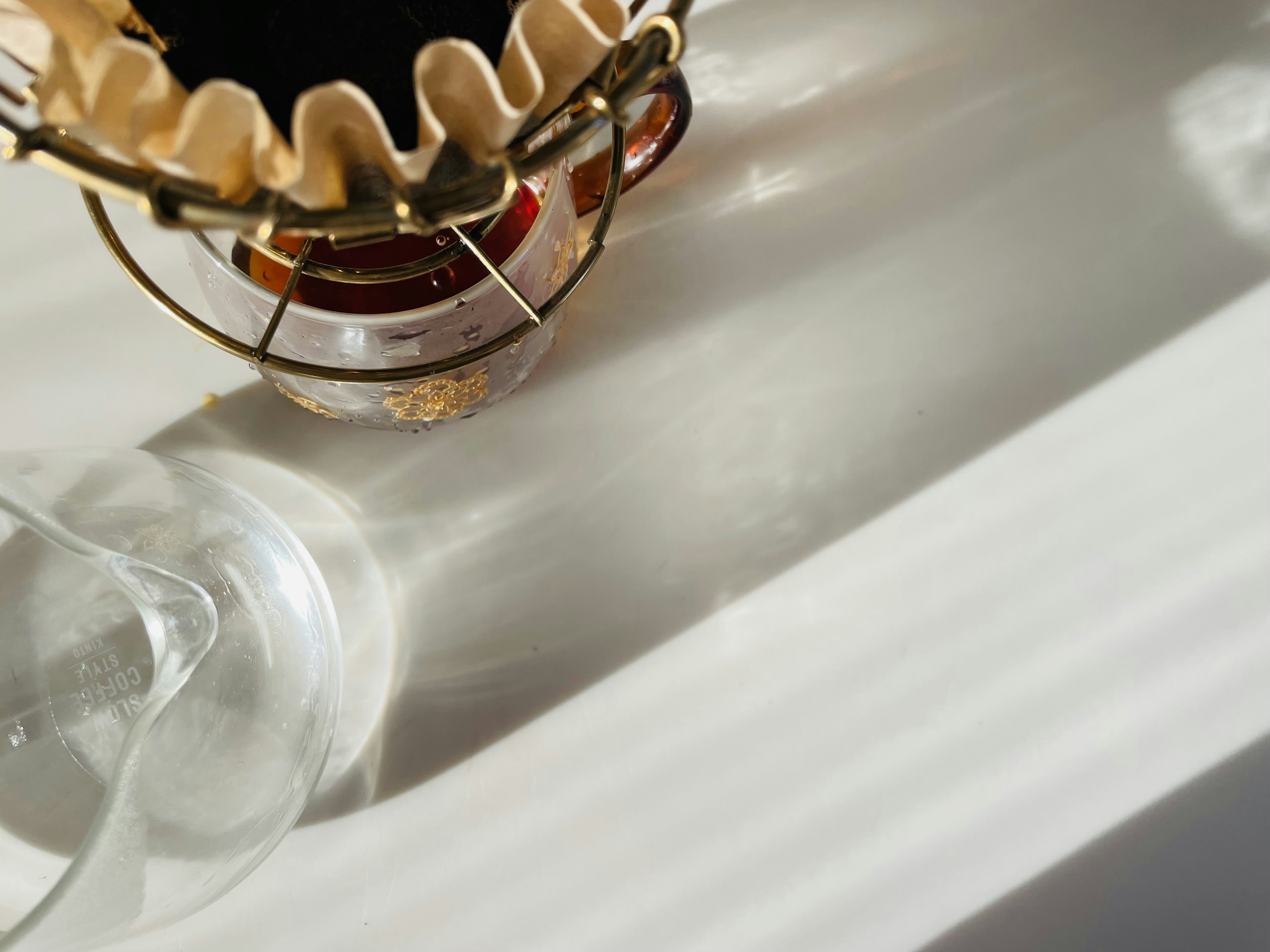 Coffee brewing equipment and glass casting reflections on a white table