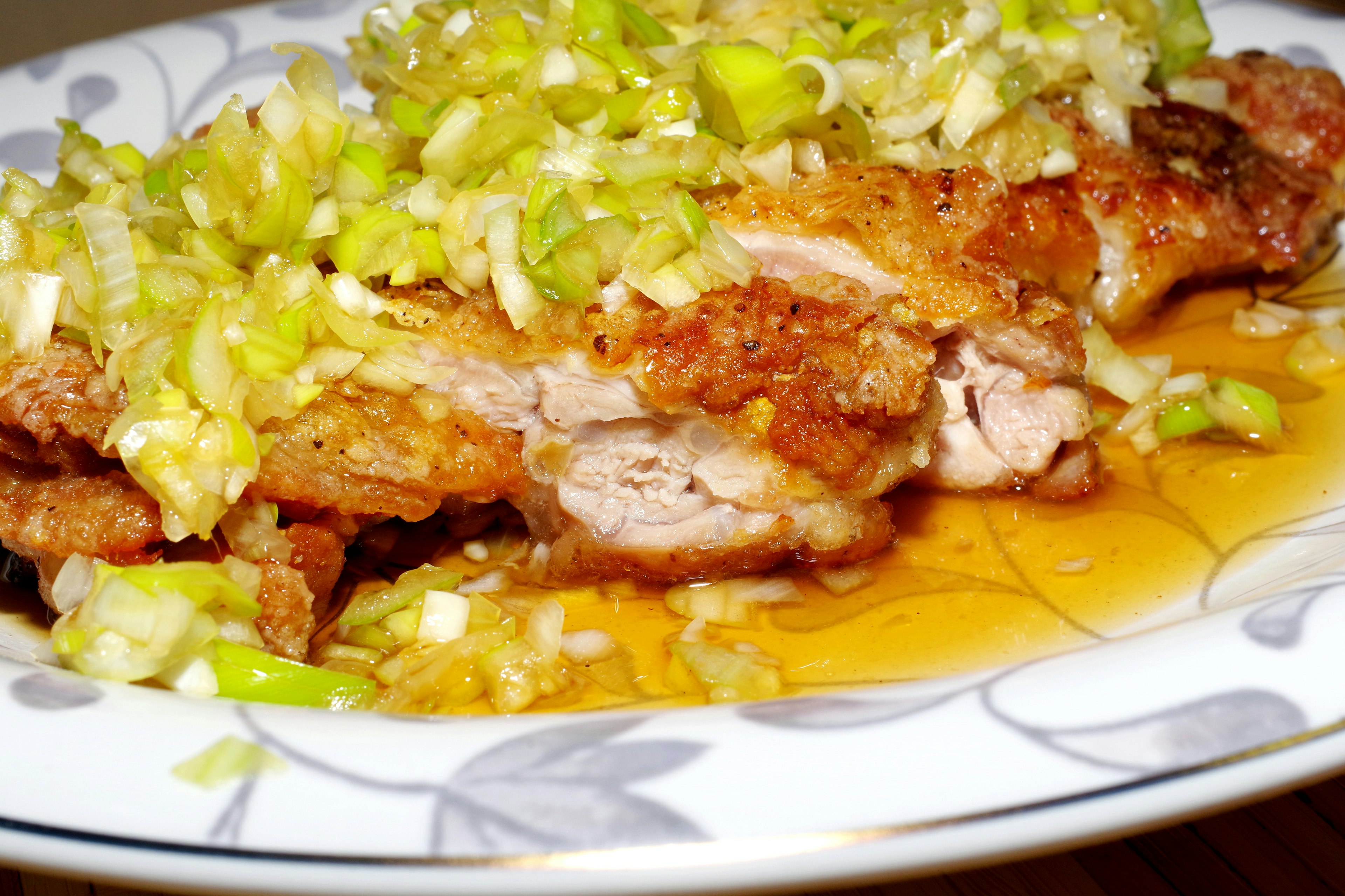 Crispy chicken topped with chopped green onions on a decorative plate