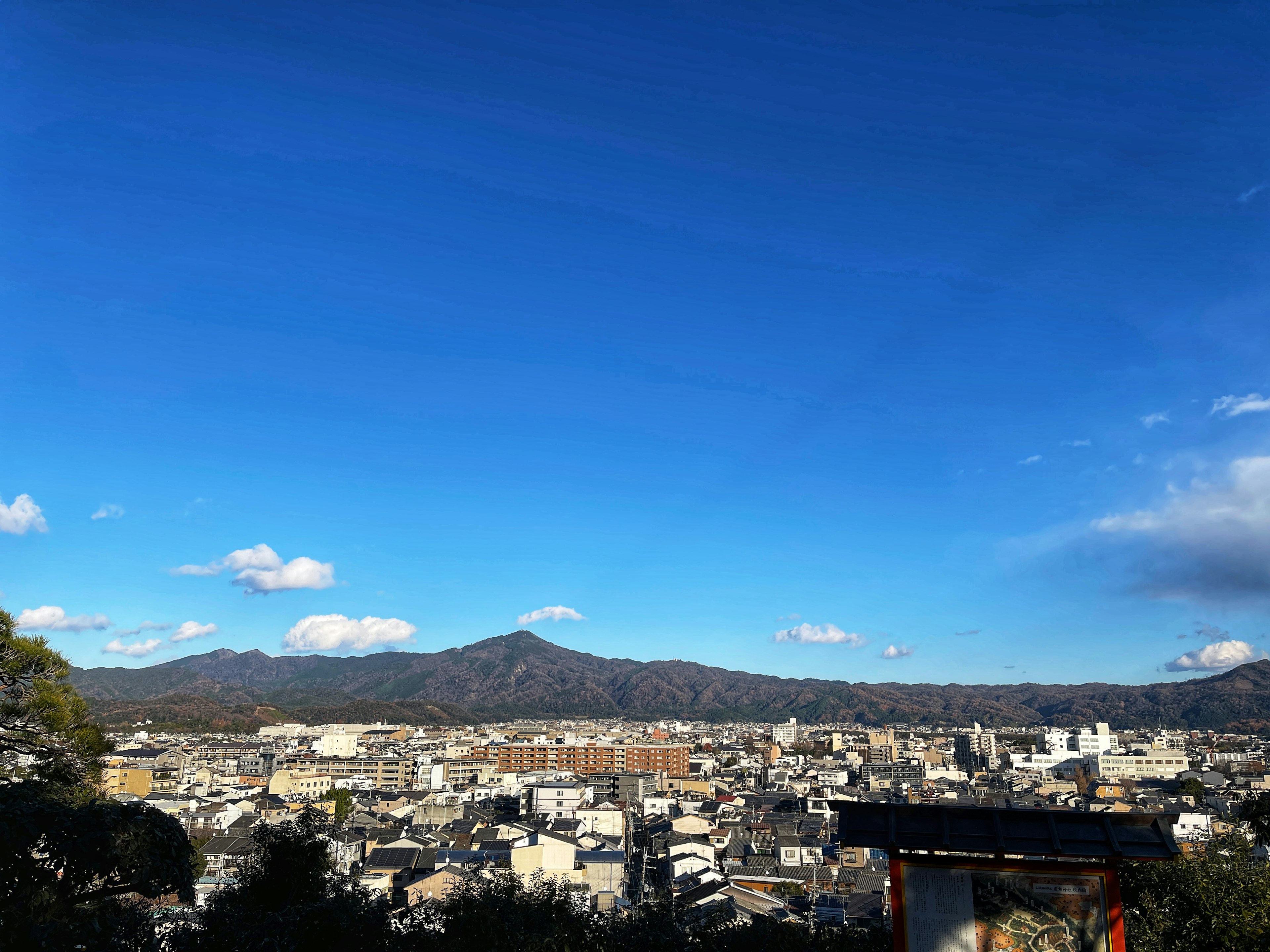 Panoramic view of Kyoto cityscape under blue sky with mountains