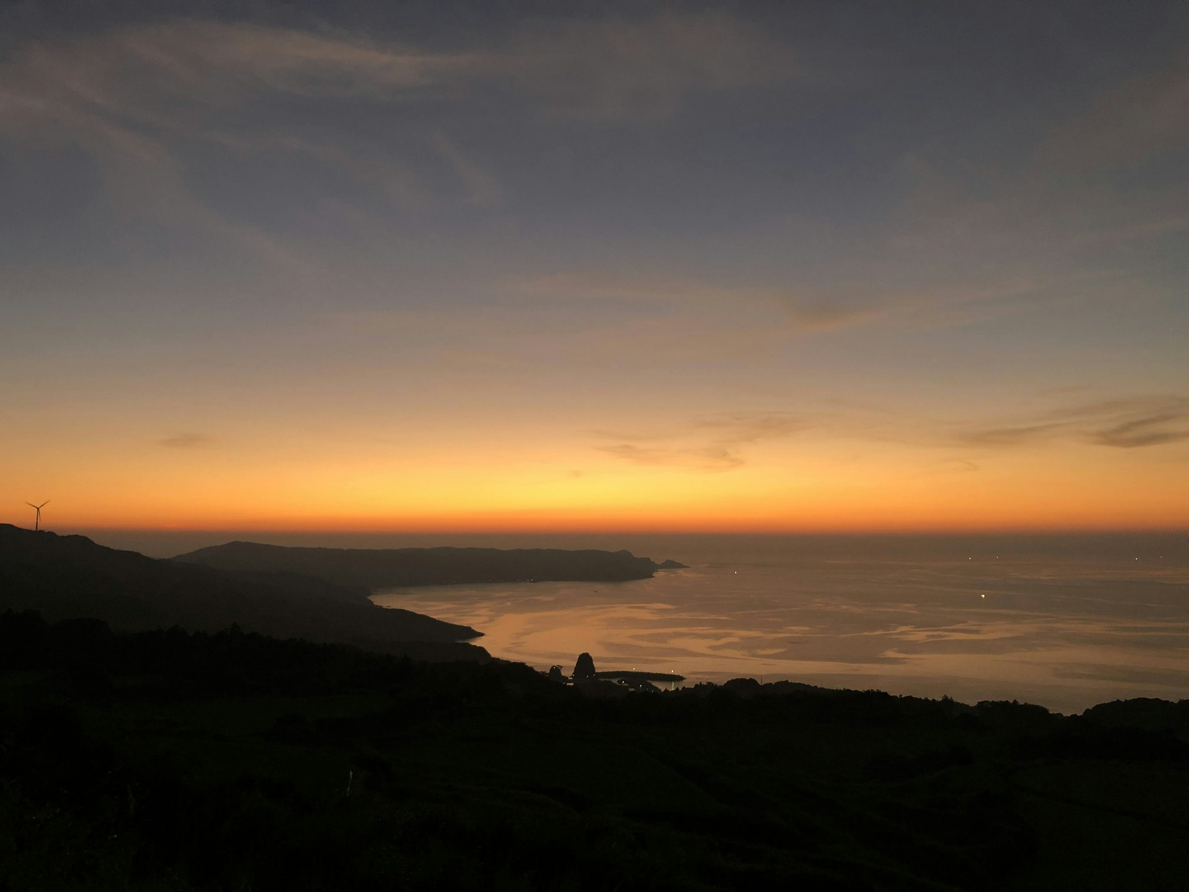 Malersiche Küstenansicht bei Sonnenuntergang mit orange-blauem Farbverlauf im Himmel