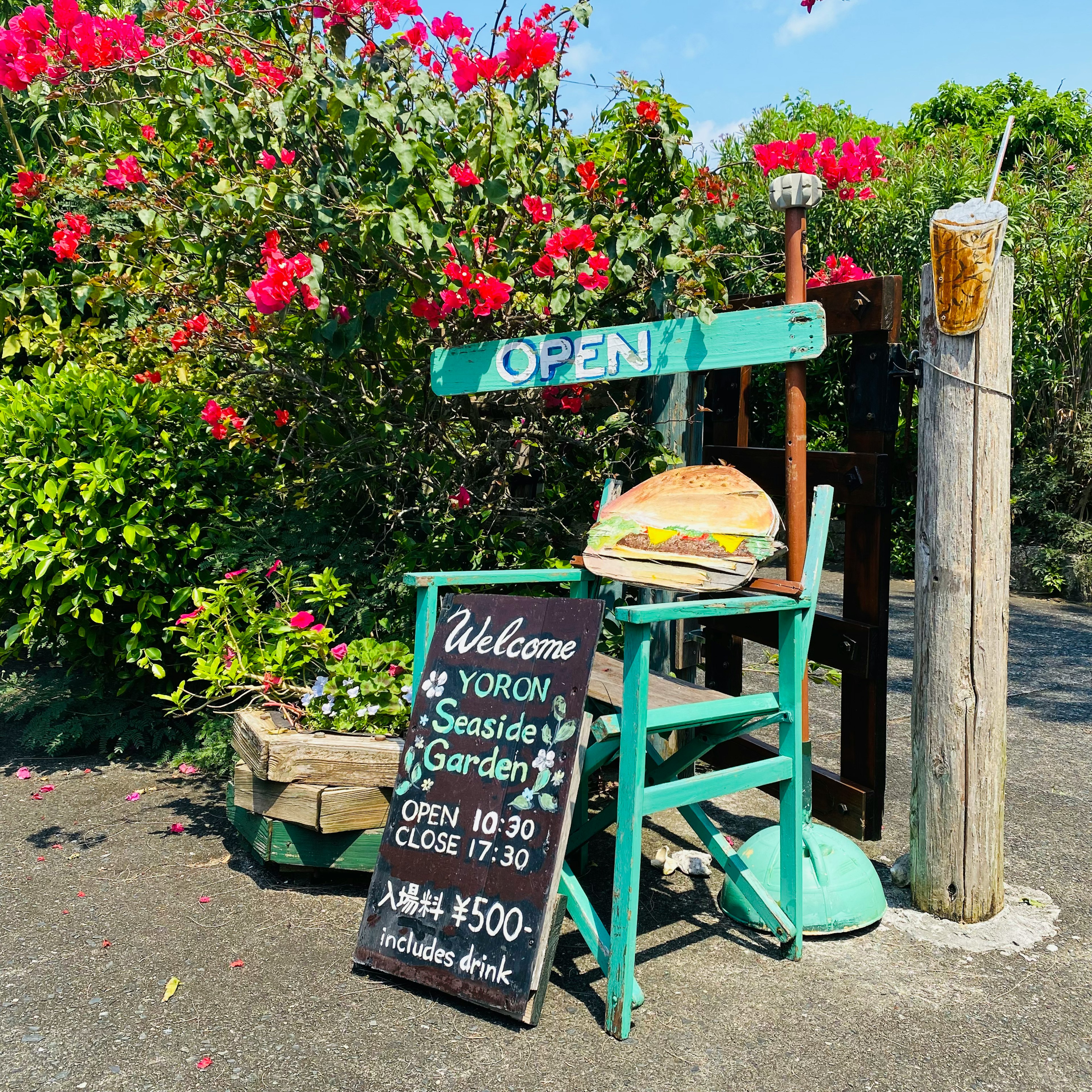 Open sign at Yoron's seaside garden surrounded by flowers