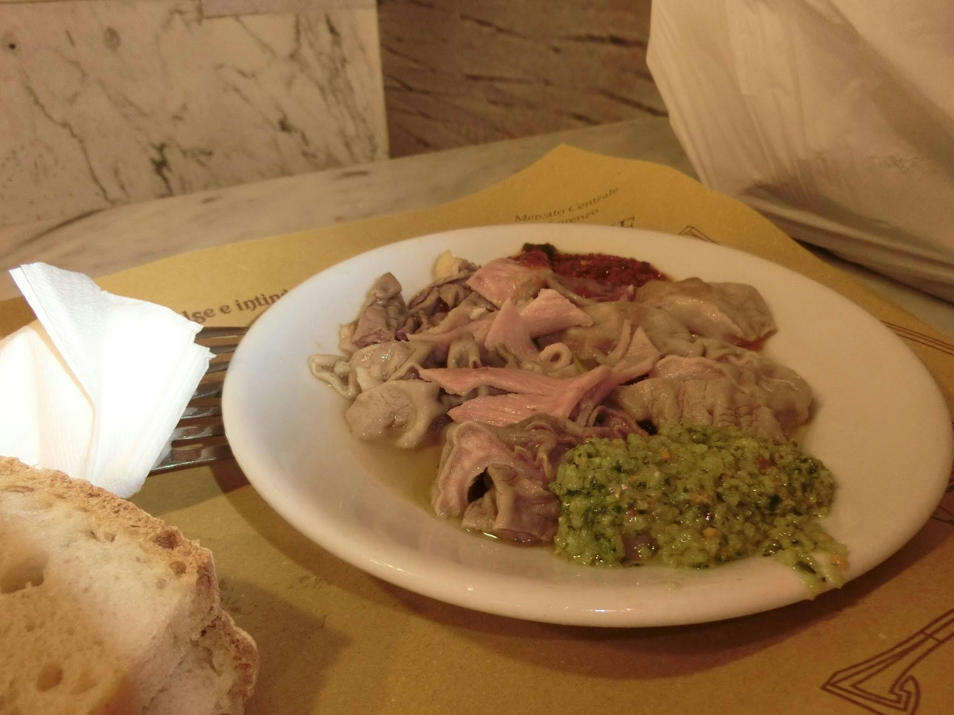 Plate of assorted meat dishes with green sauce and bread