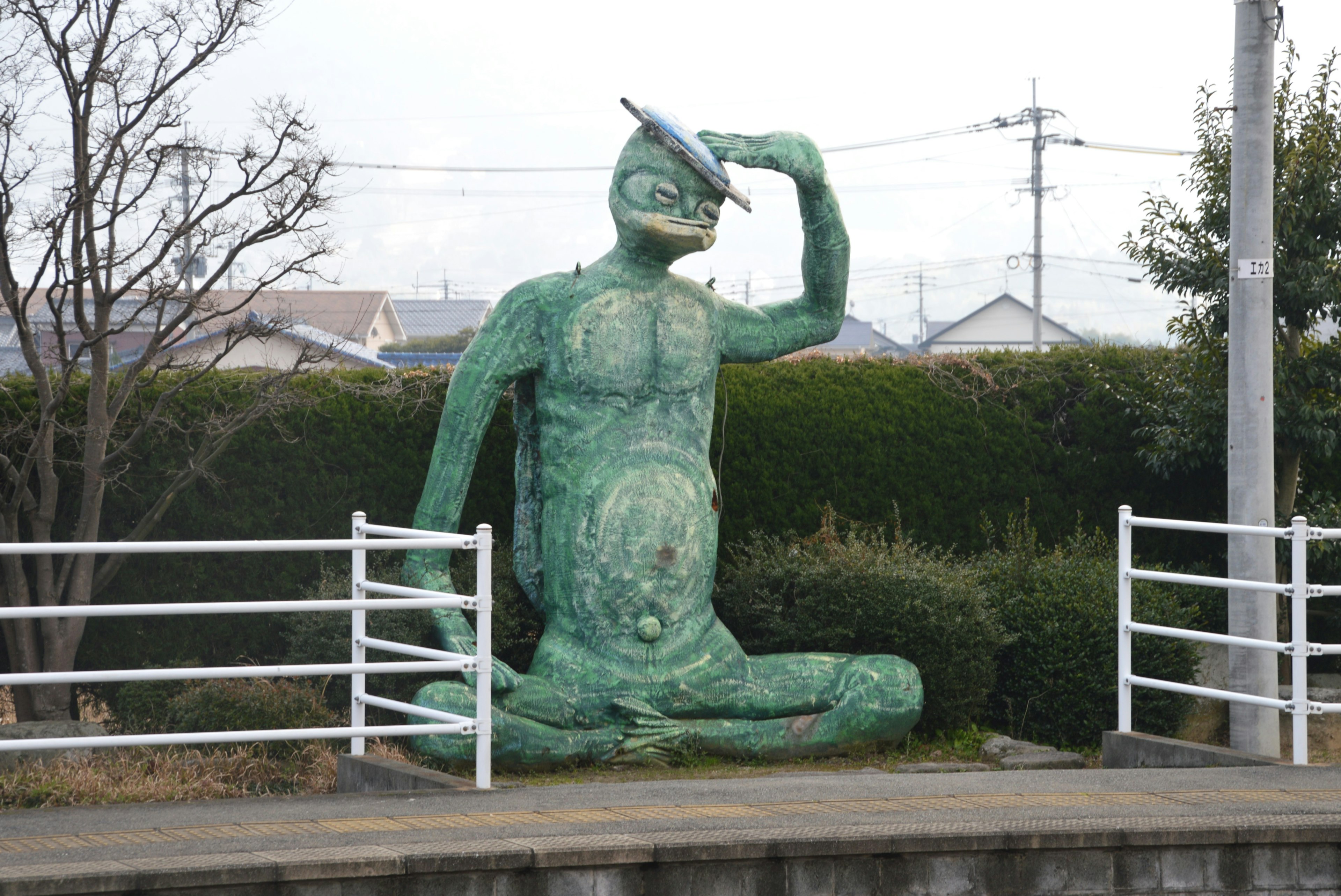 Estatua verde sentada saludando con un sombrero