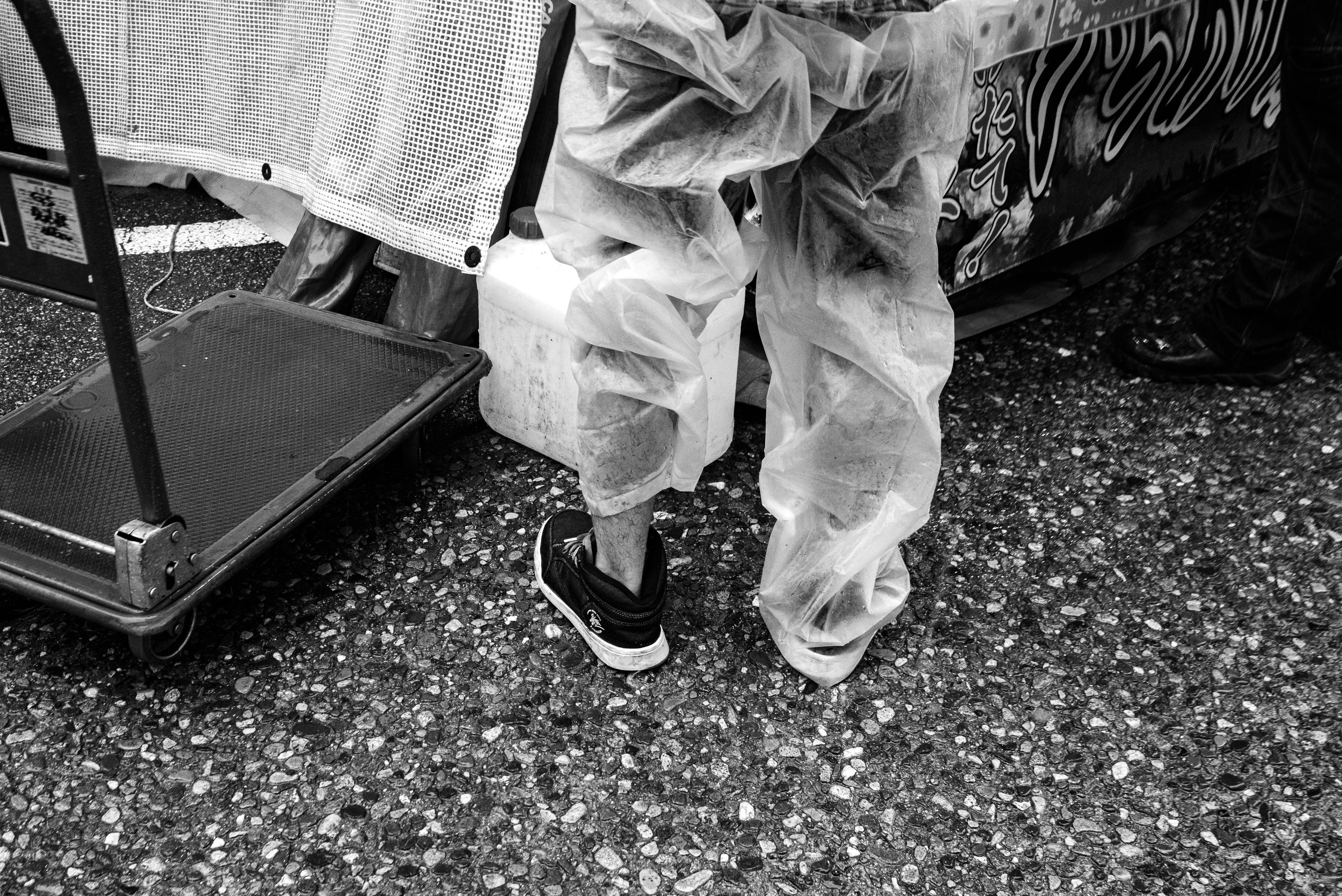 Black and white image showing the legs of a person wearing a plastic apron