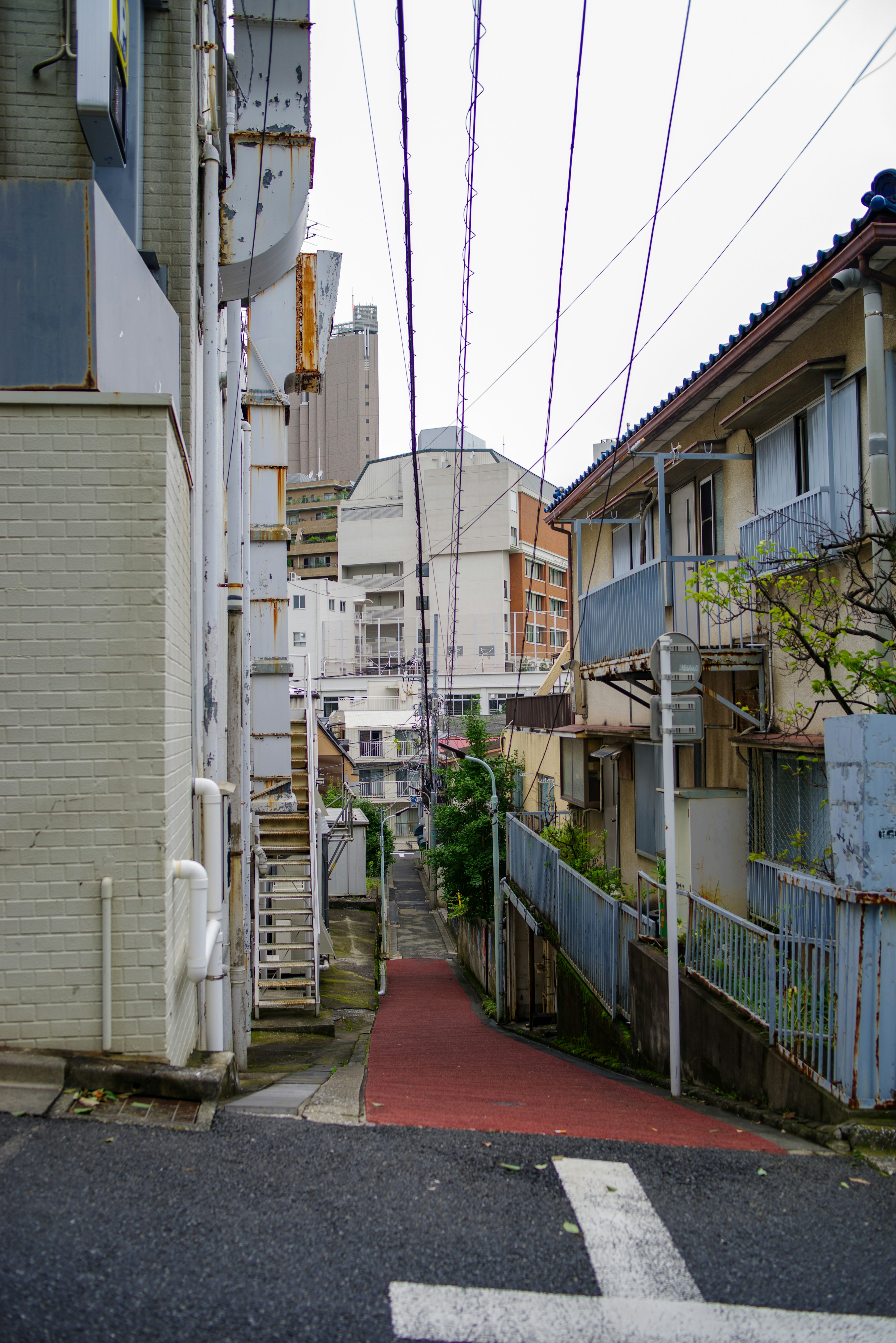 Calle estrecha flanqueada por edificios y líneas eléctricas visibles